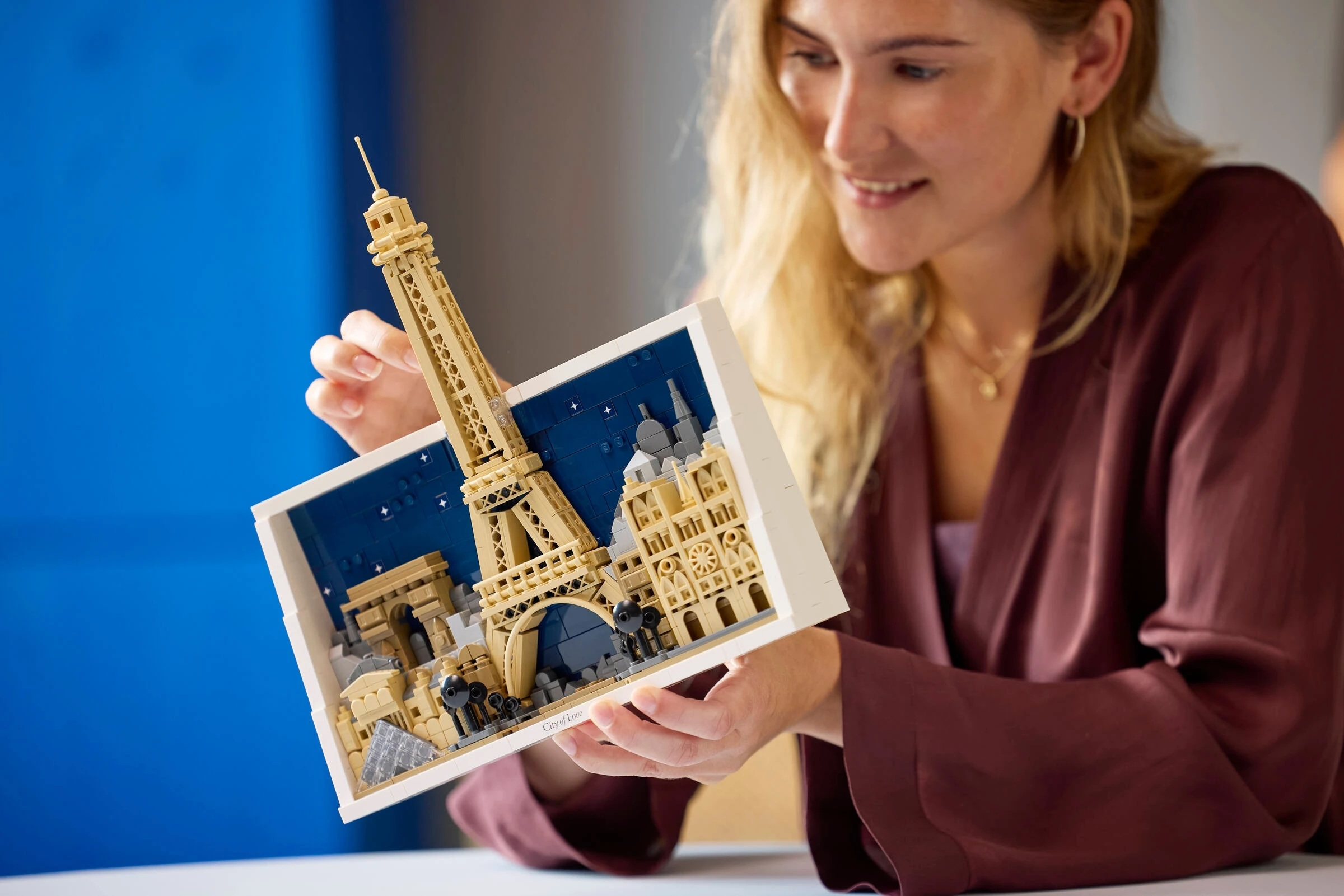 Kobieta trzyma model Lego Wieży Eiffla i Paryża.