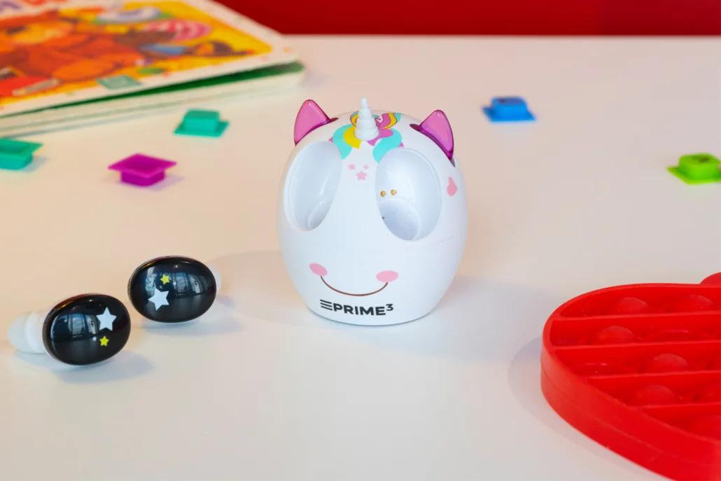 Ładowarka jednorożec ze słuchawkami w gwiazdki, książką i zabawkami na stole.
