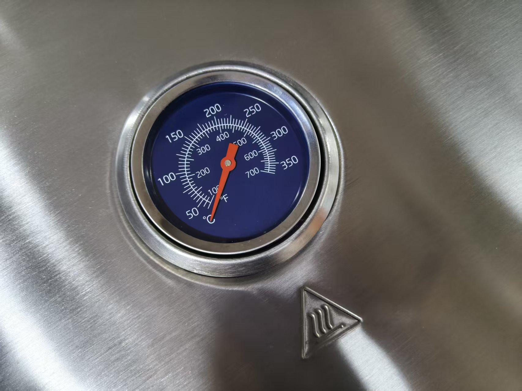 Ein Grillthermometer mit rotem Zeiger auf 150°F bei 50°C auf Edelstahl.