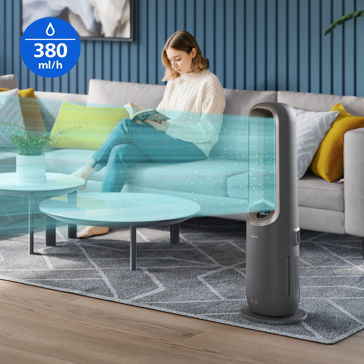 A woman reads on a couch as a grey humidifier releases a cool mist.