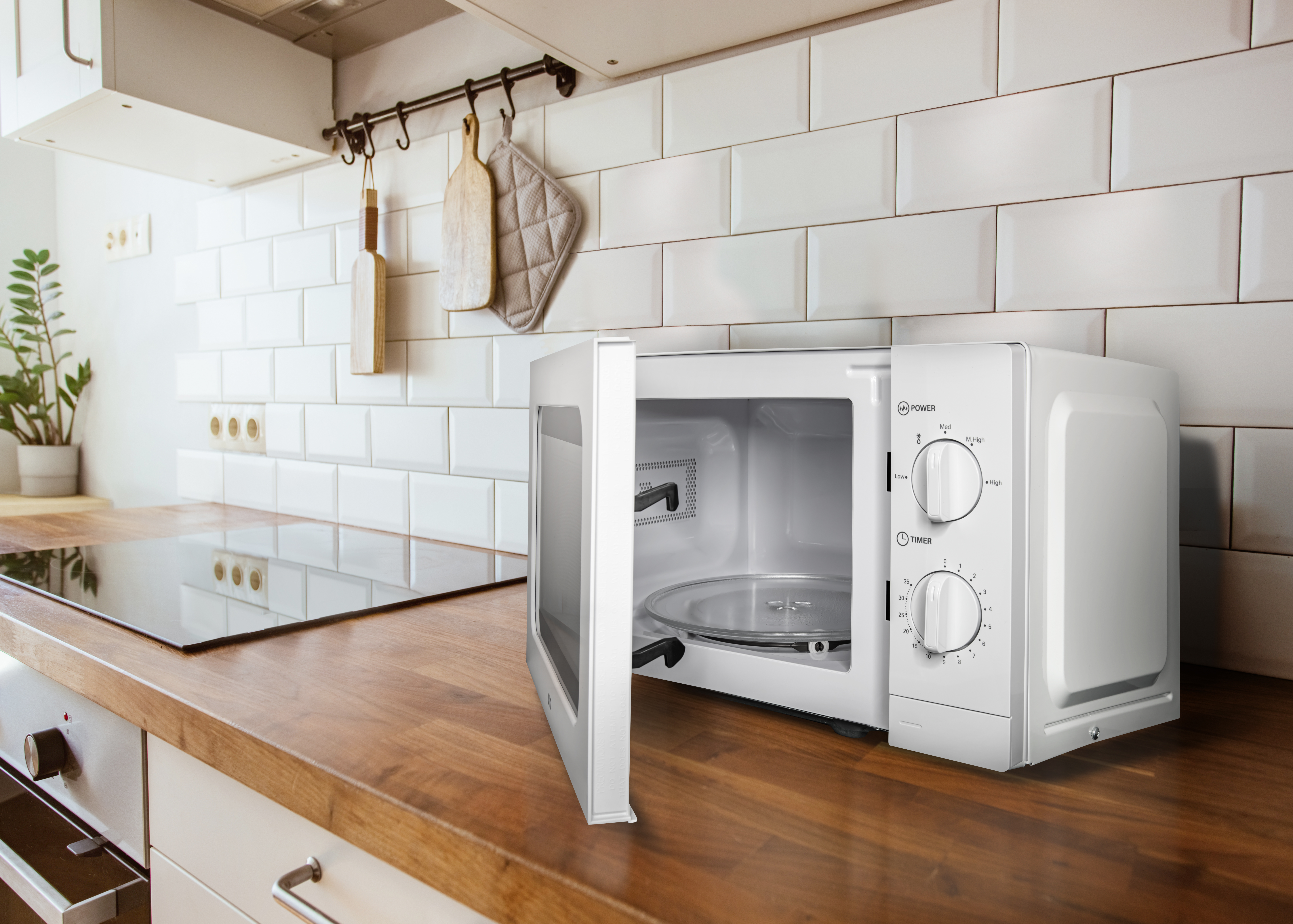 Biała kuchenka mikrofalowa z otwartymi drzwiami na drewnianym blacie, białe płytki.