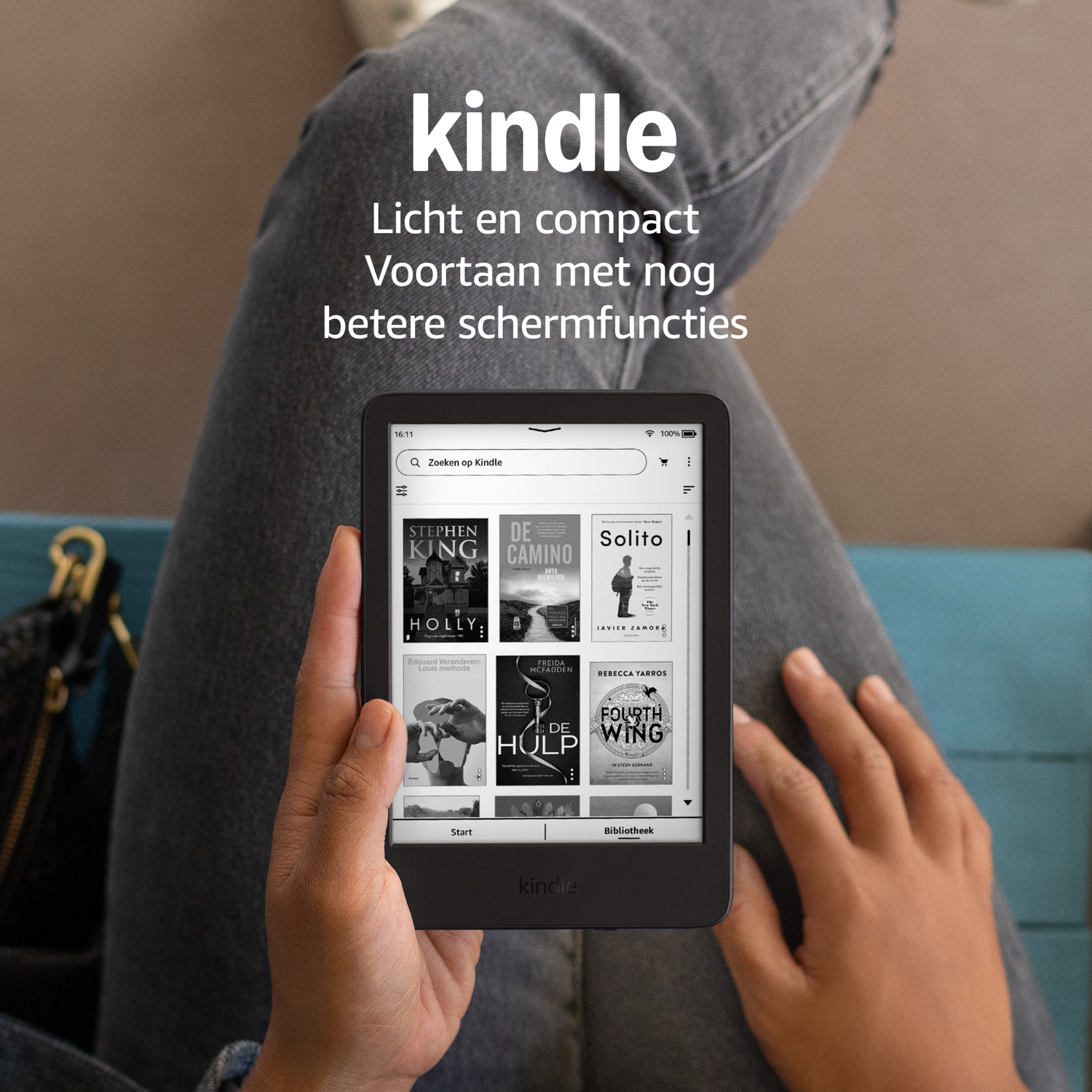 A person holds a Kindle e-reader displaying book covers on its screen.