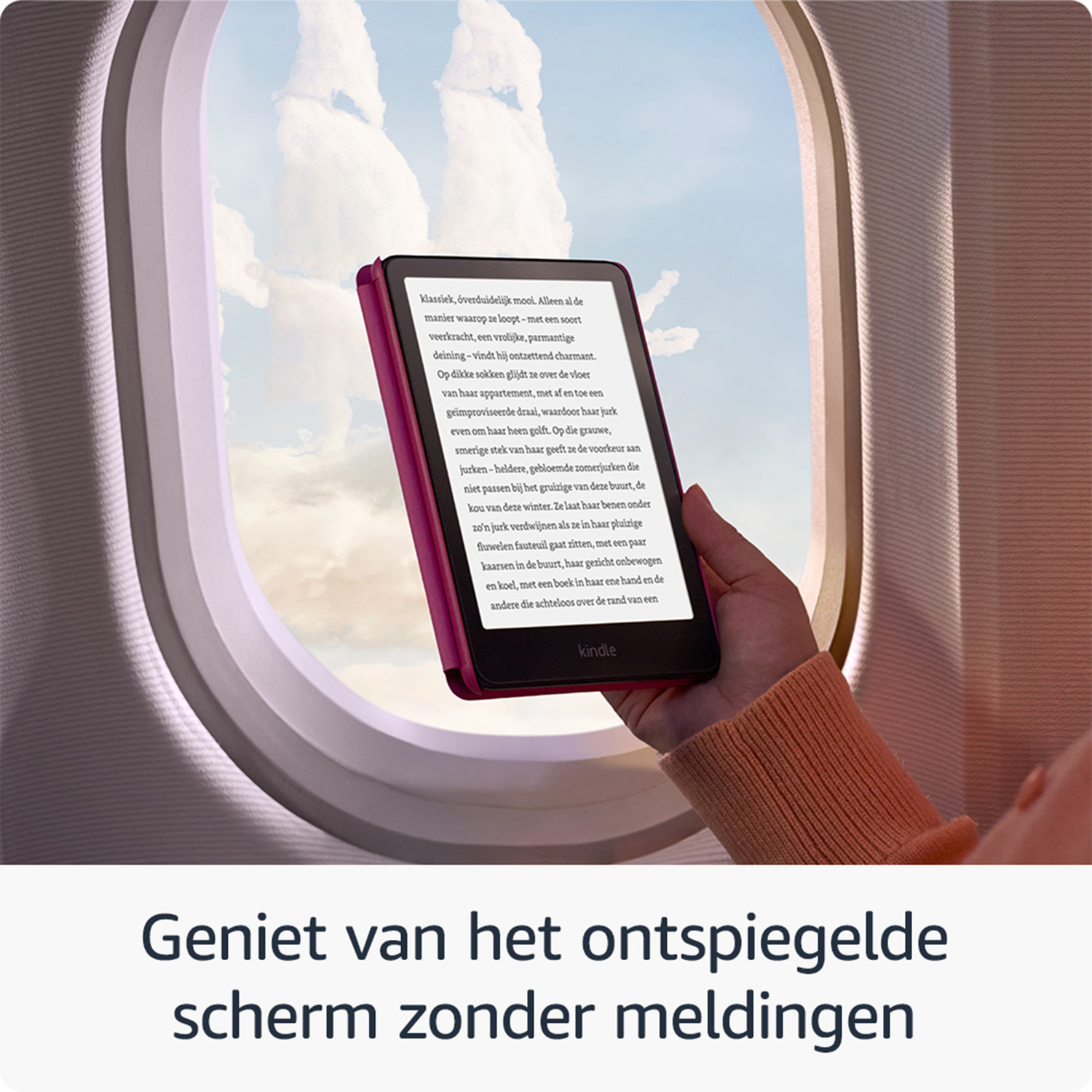 A hand holds a Kindle e-reader in front of an airplane window.