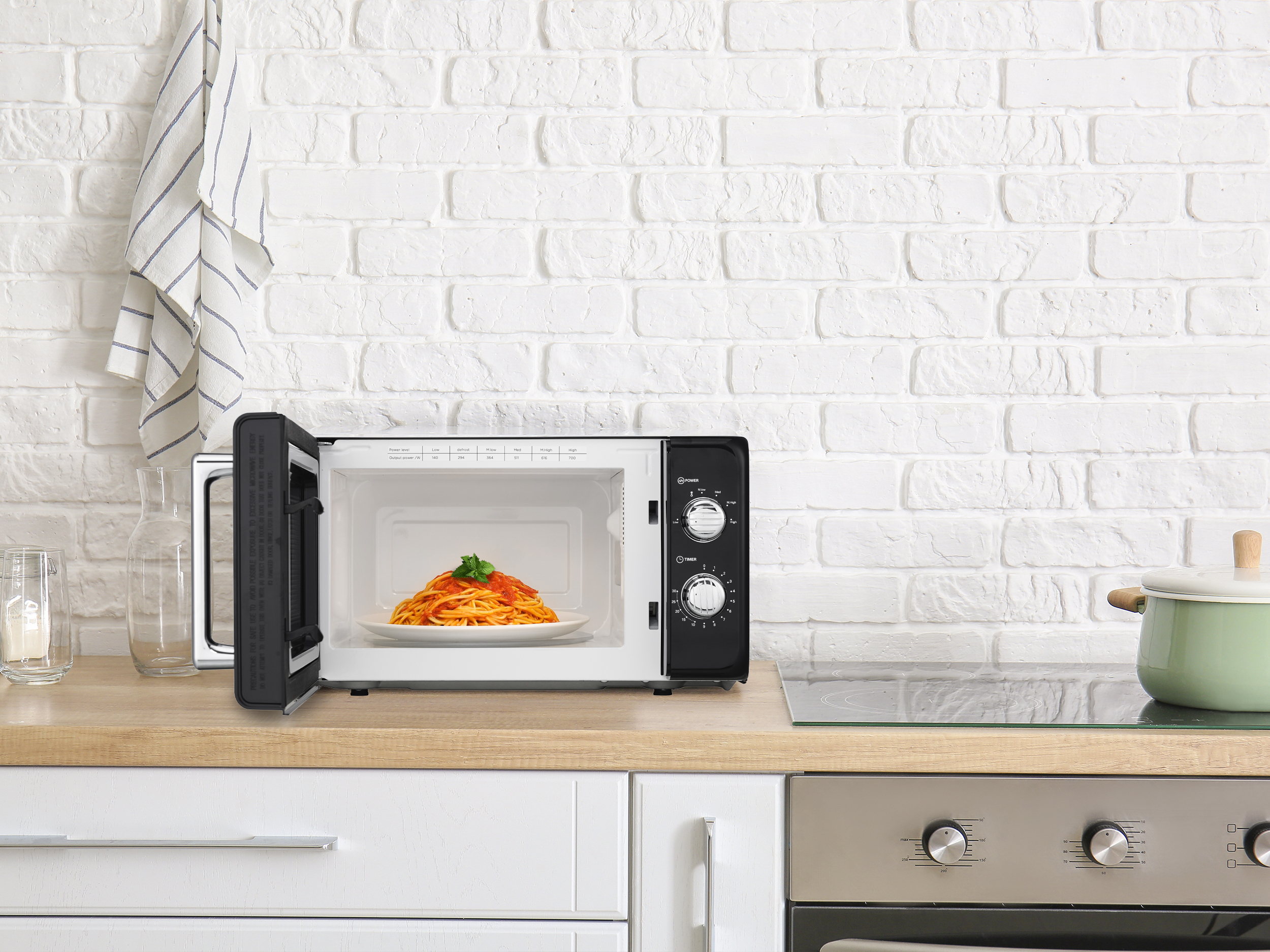 Otwarta czarna kuchenka mikrofalowa z talerzem spaghetti w środku.