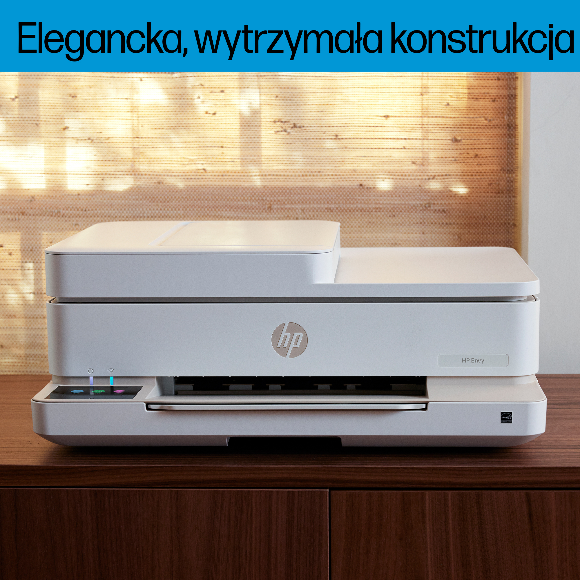Biała drukarka HP Envy stoi na ciemnej drewnianej szafce. W tle znajduje się teksturowana ściana.