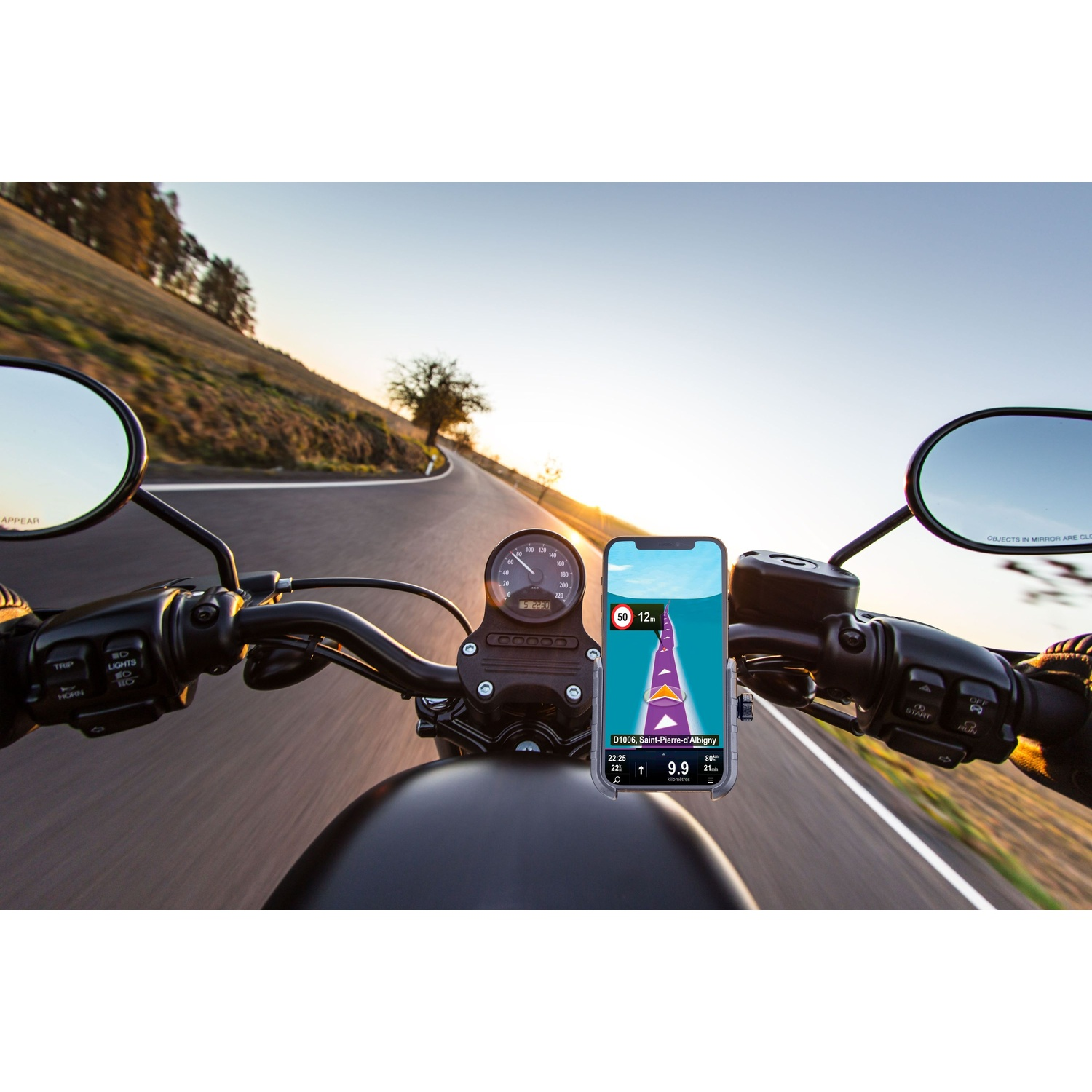 Motociclista naviga con telefono su strada tortuosa al tramonto.