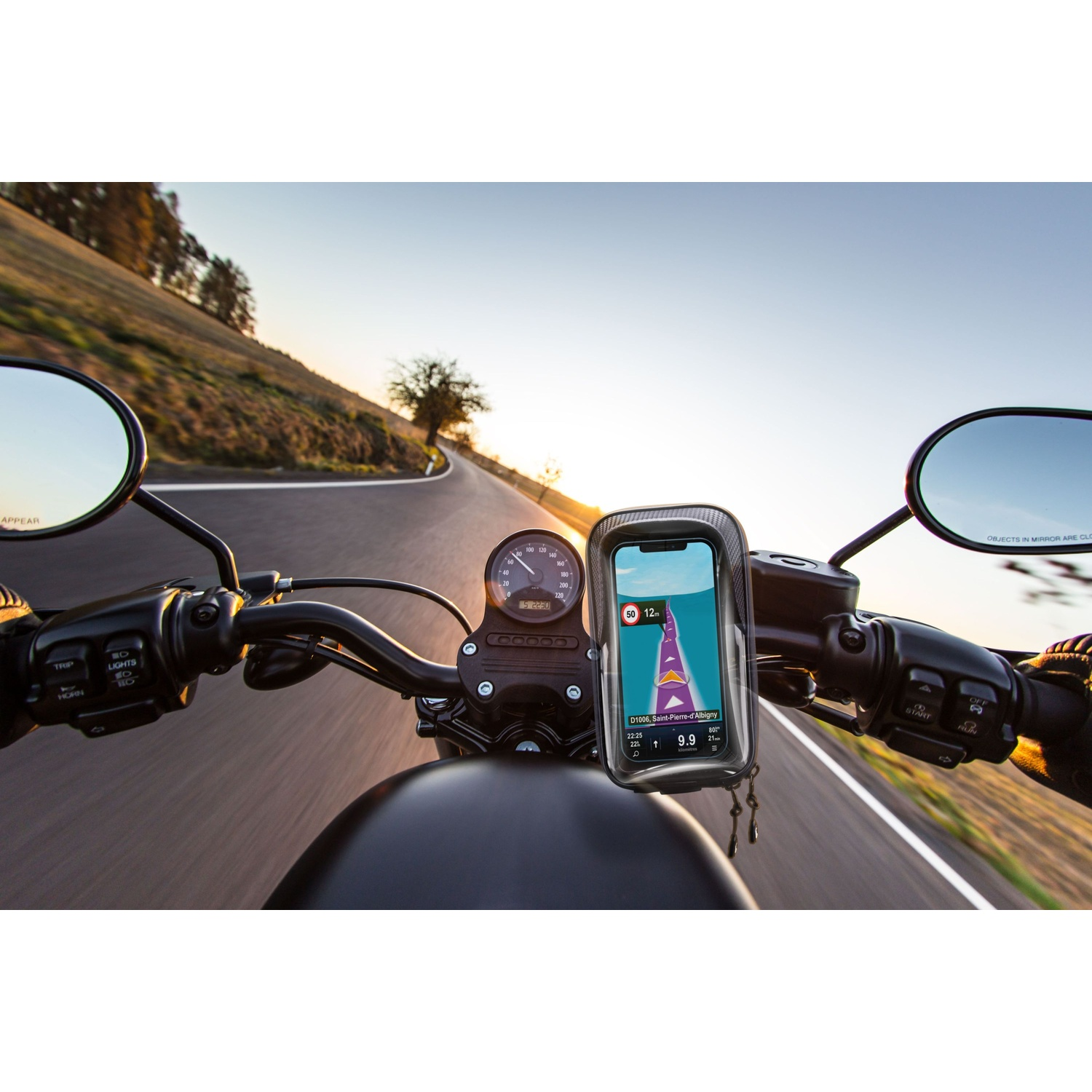 Motociclista naviga con supporto per telefono su strada tortuosa al tramonto.