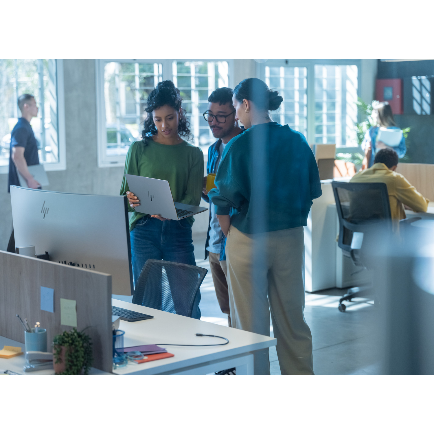 People in a modern office, gathered around a laptop.