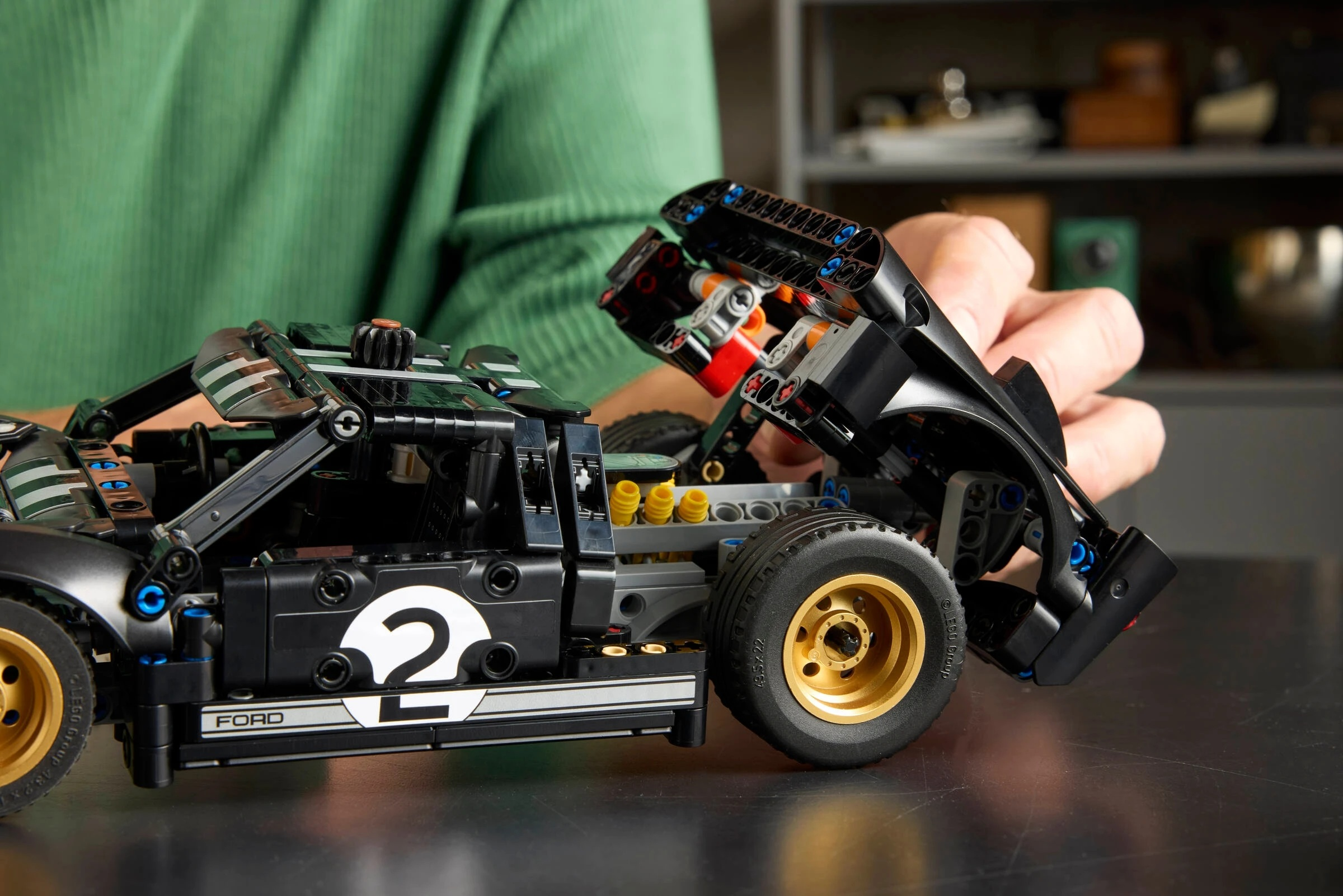 Czarny samochód wyścigowy Lego Ford GT ze złotymi kołami. Ręka podnosi tylny spojler.