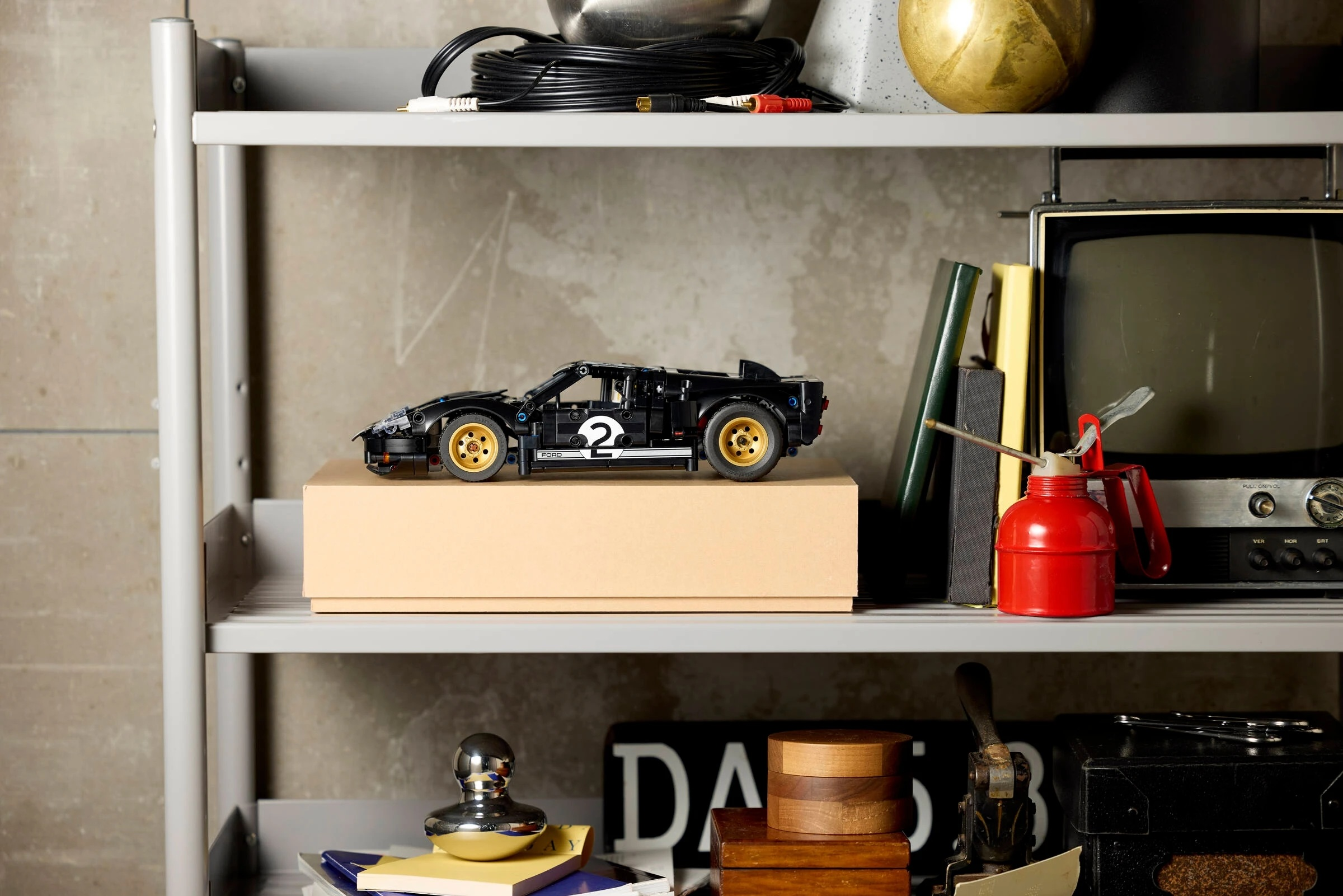 Czarny samochód wyścigowy Lego ze złotymi felgami stoi na pudełku.