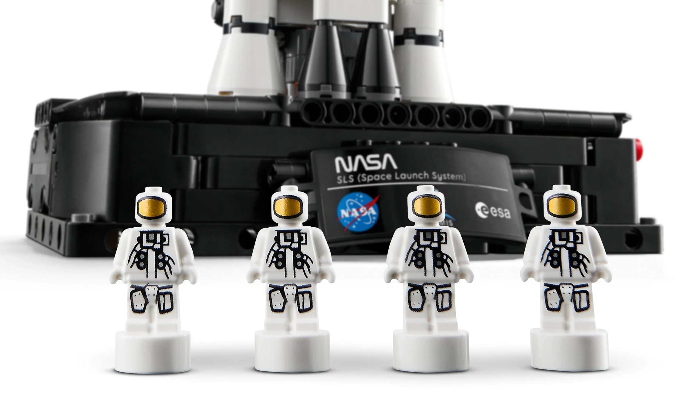 Czterech astronautów Lego przed czarnym modelem rakiety z logo NASA.