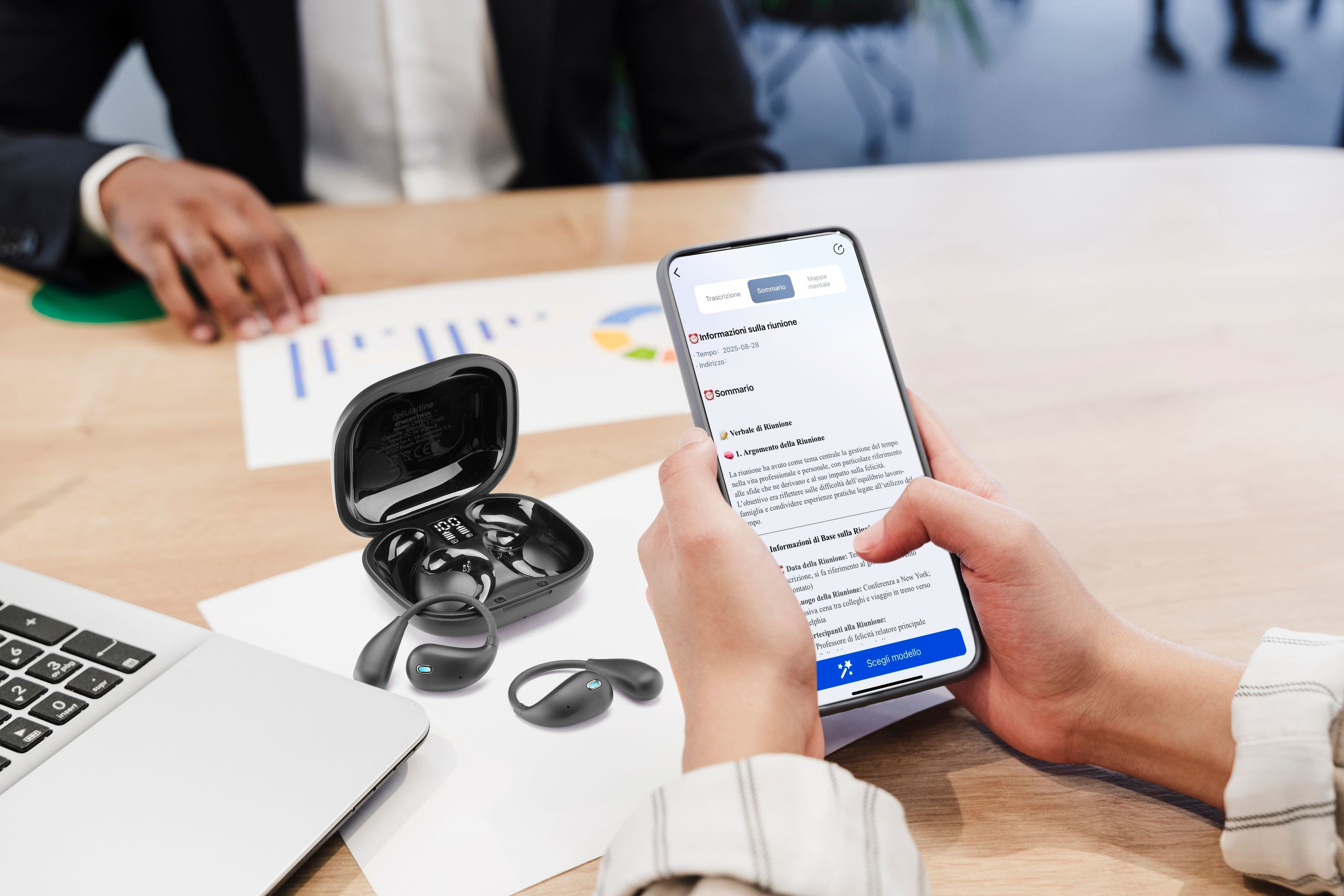 Siyah kulaklıklar, dizüstü bilgisayar ve telefon bulunan masada şarj kutusunda.