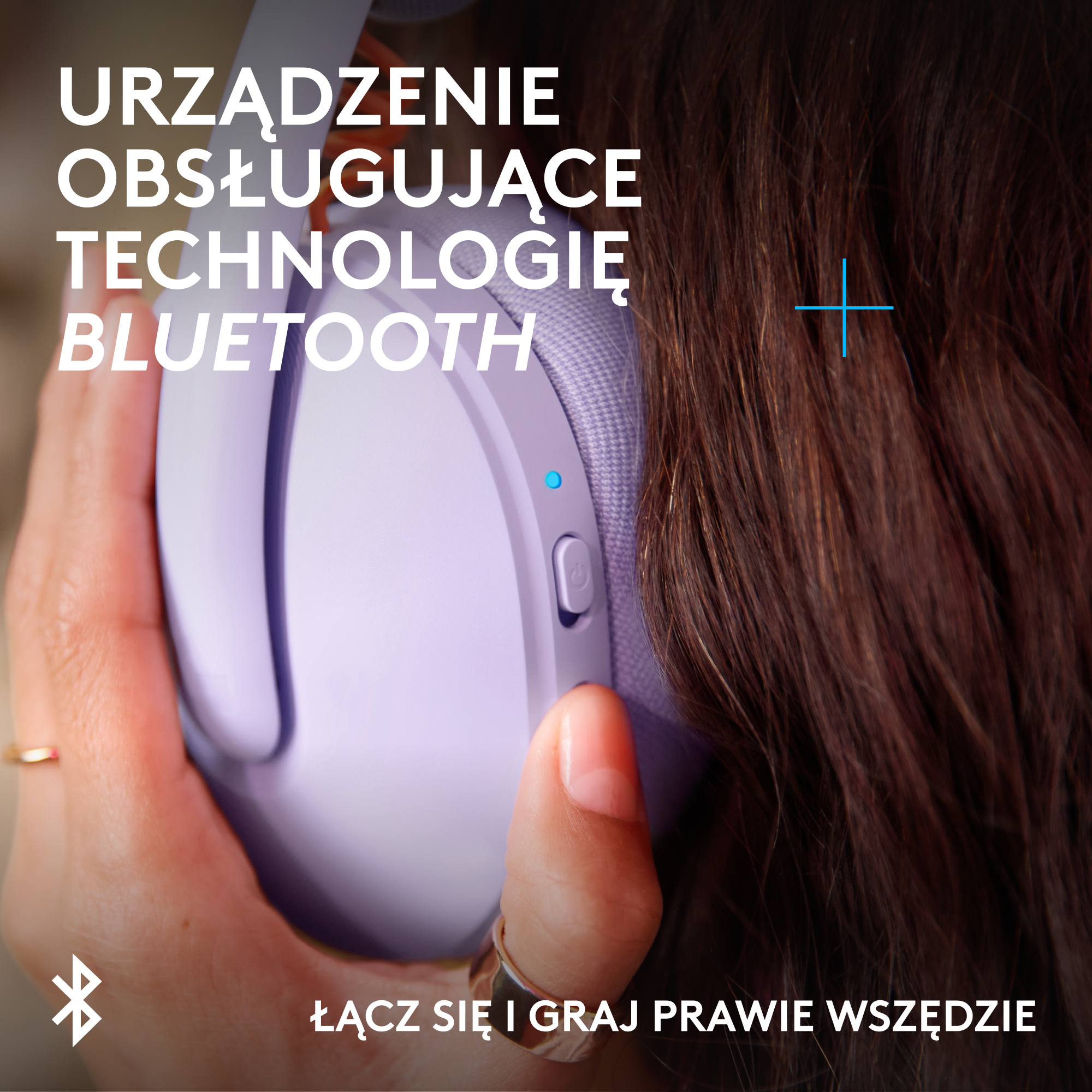 Osoba trzymająca fioletowe słuchawki z symbolem Bluetooth. Zbliżenie.
