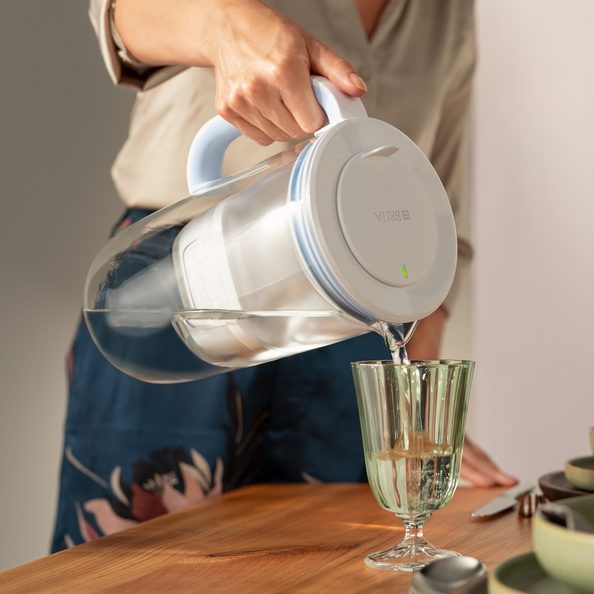 Una persona versa acqua da una caraffa Brita in un bicchiere.