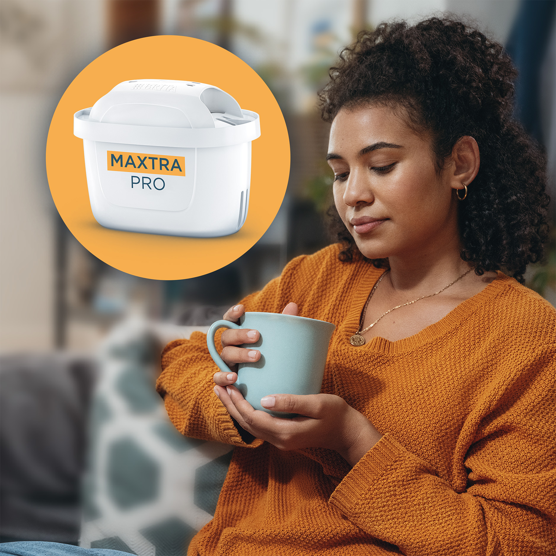 Donna con maglione arancione tiene una tazza azzurra. Filtro Brita MAXTRA PRO in cerchio.