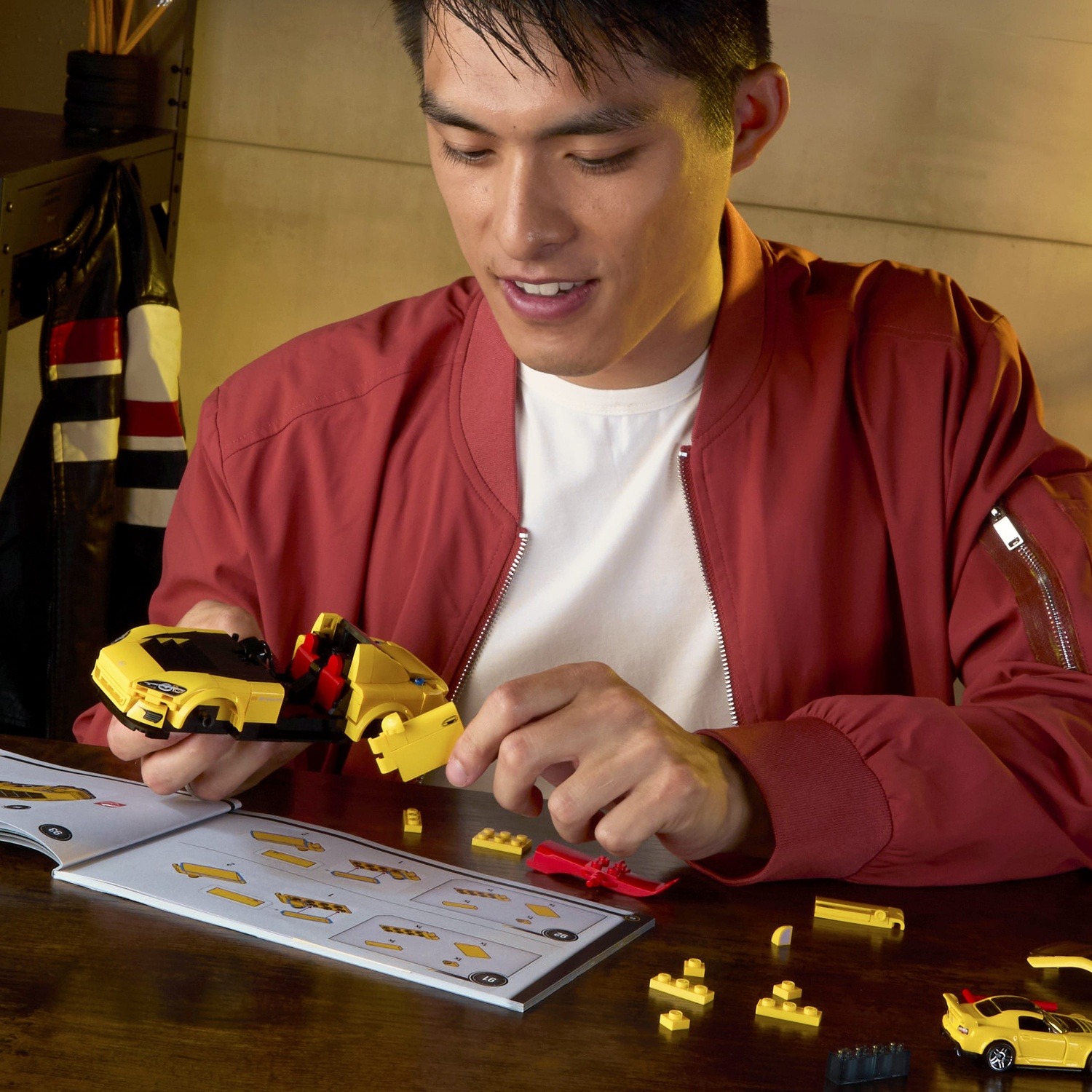 Un uomo costruisce un'auto Lego gialla seguendo le istruzioni.
