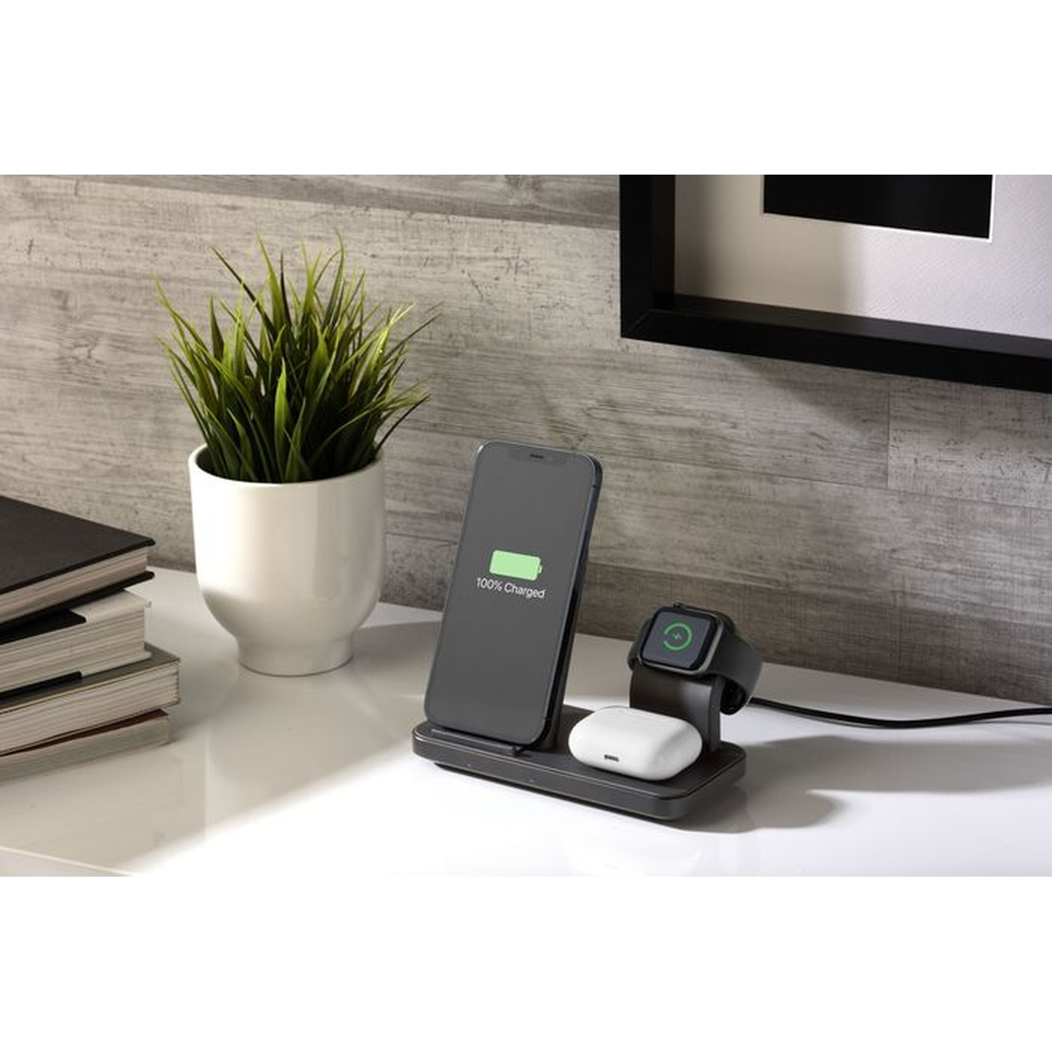 Un supporto di ricarica wireless con smartphone, smartwatch e auricolari su una scrivania.