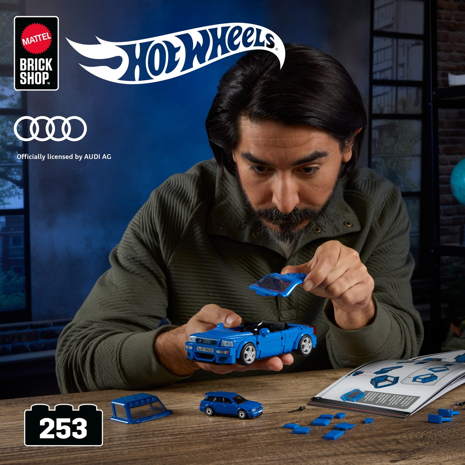 Uomo costruisce replica Lego blu Audi Sport quattro. Istruzioni sul tavolo.