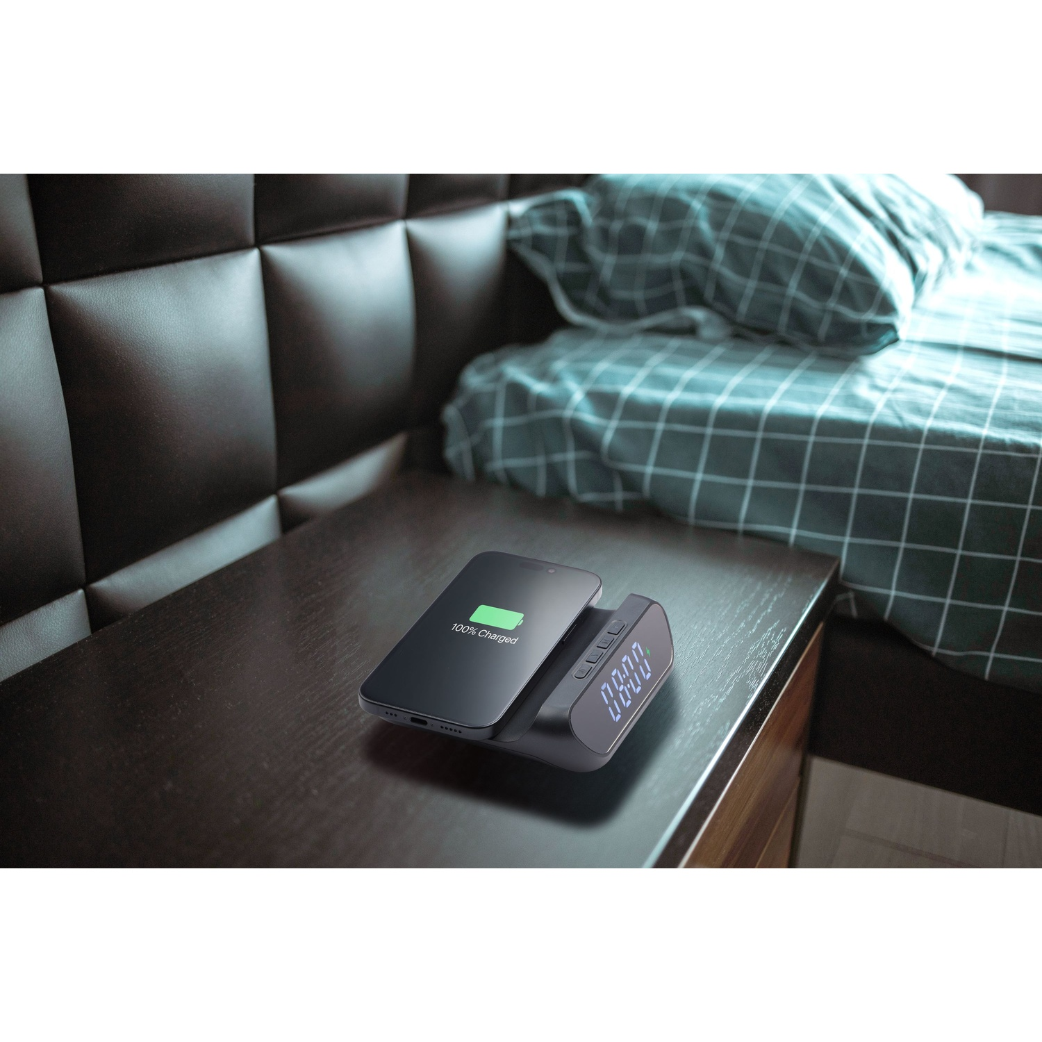 Uno smartphone si carica su un comodino, accanto a una sveglia digitale.