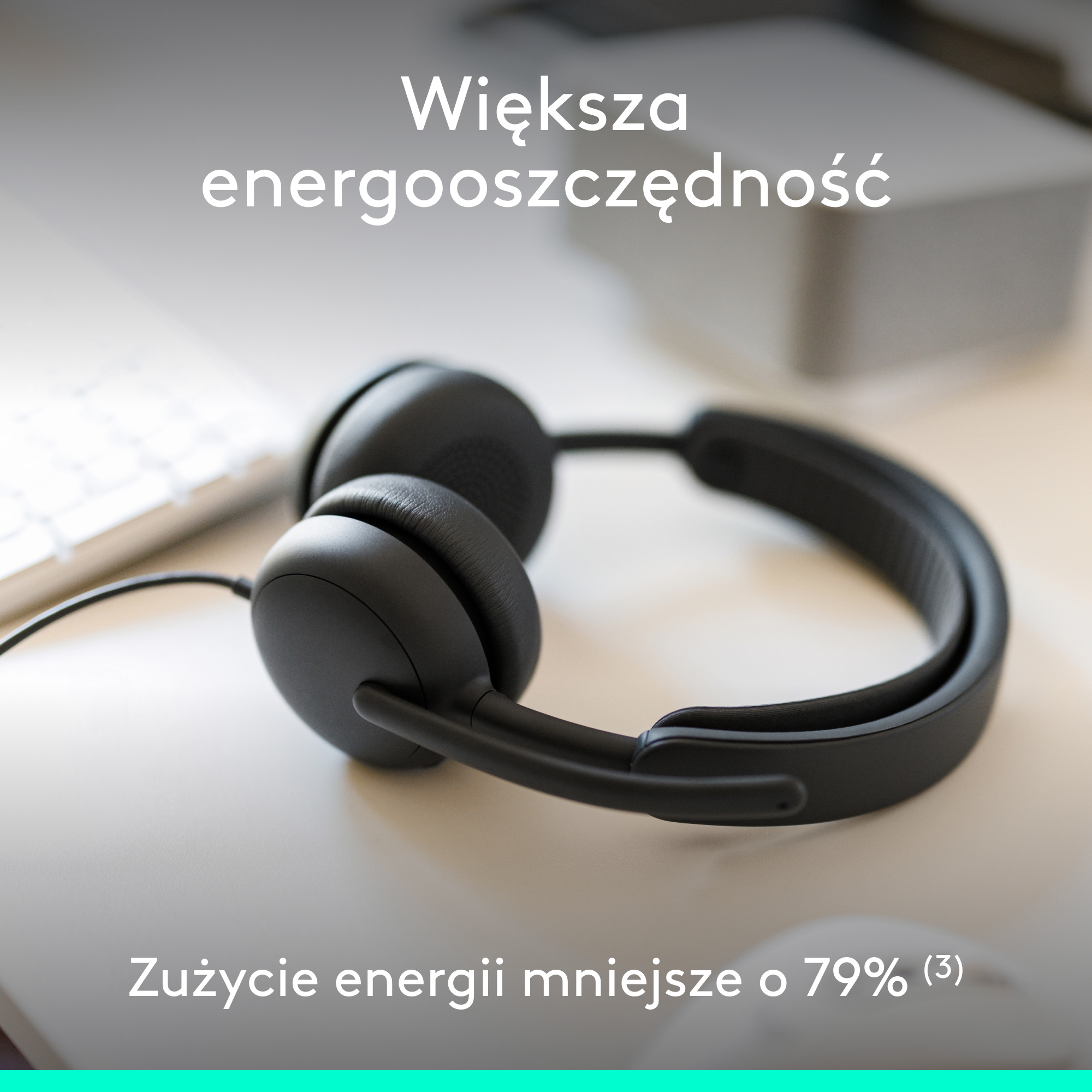 Czarne słuchawki na biurku obok klawiatury. Tekst: "Większa energooszczędność".