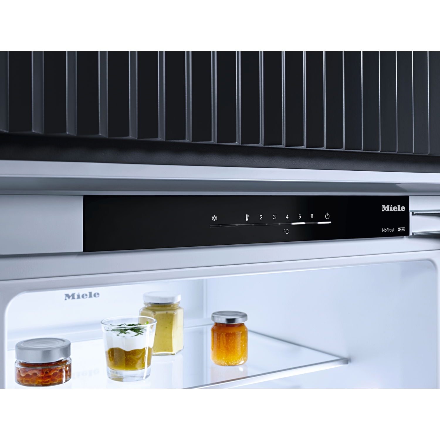 Miele refrigerator interior with three jars and shelves. Temperature controls.
