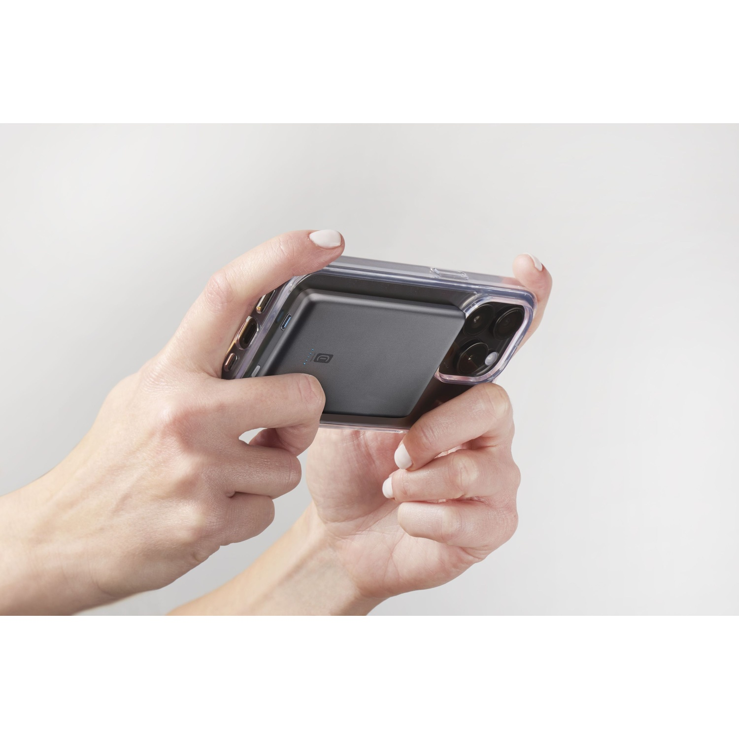 Mani che tengono uno smartphone con custodia nera e power bank.