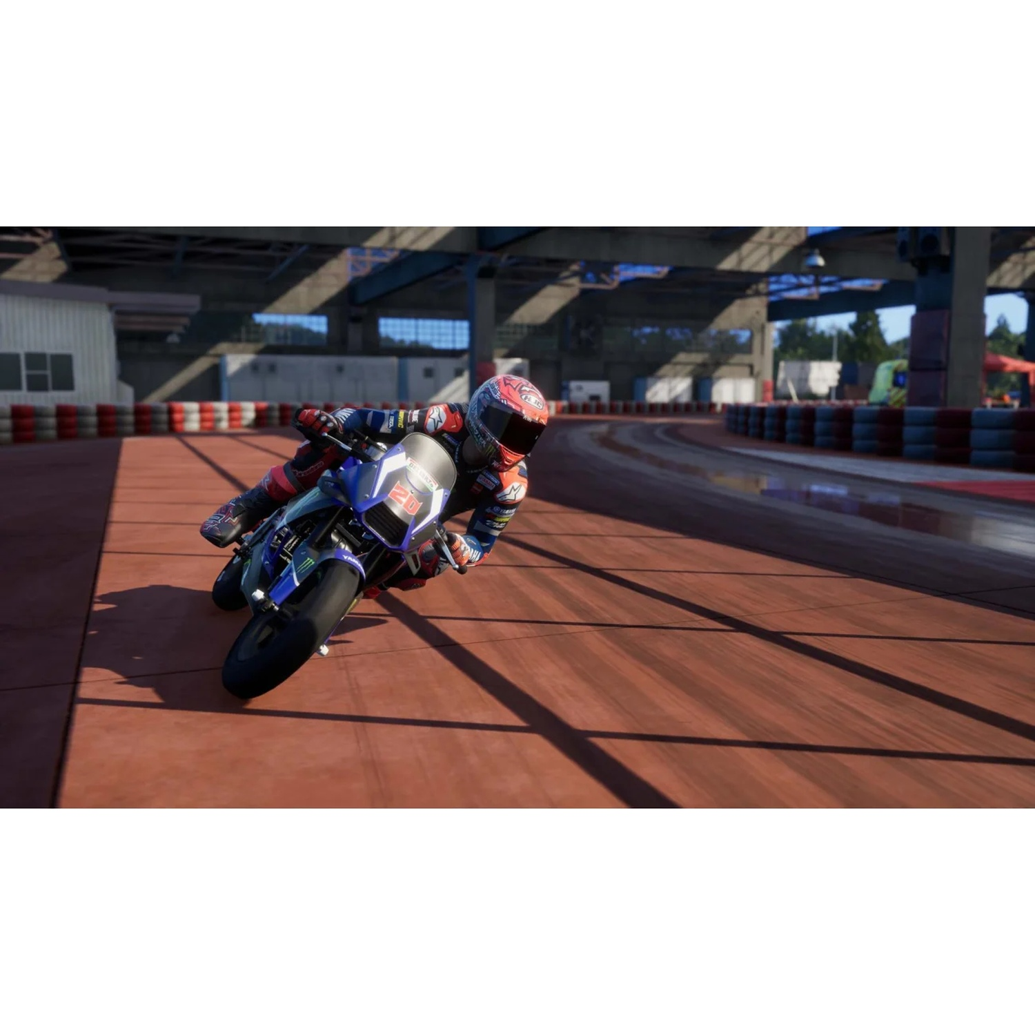 Un pilote de moto en combinaison bleu et rouge prend un virage sur une piste en bois.