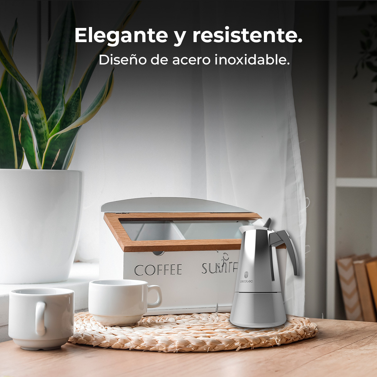 Cafetera espresso plateada con dos tazas blancas y un bote de café.