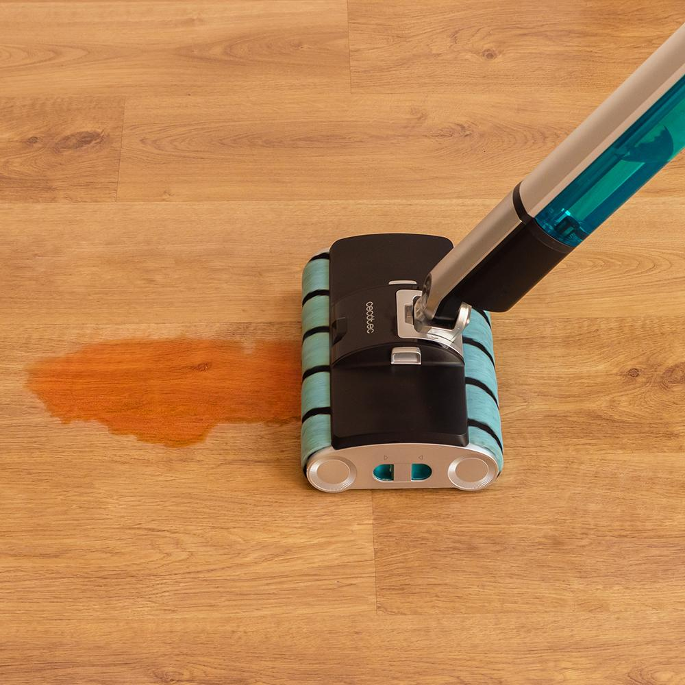 Un limpiador de suelos limpia un derrame de líquido naranja en un suelo de madera.