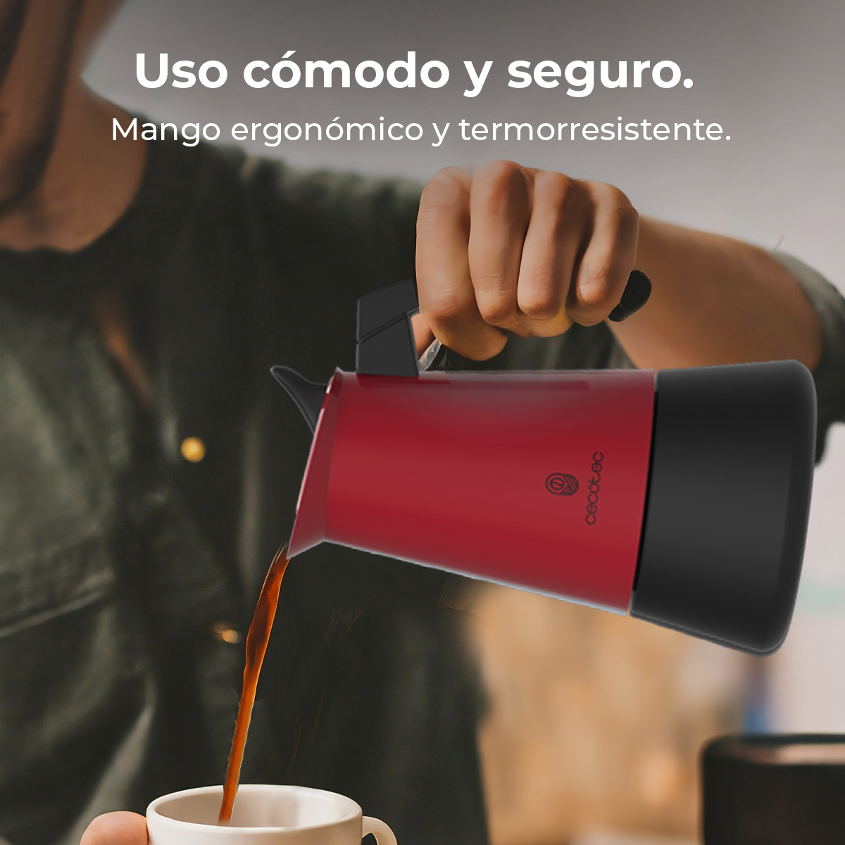 Una cafetera roja sirviendo café en una taza blanca.