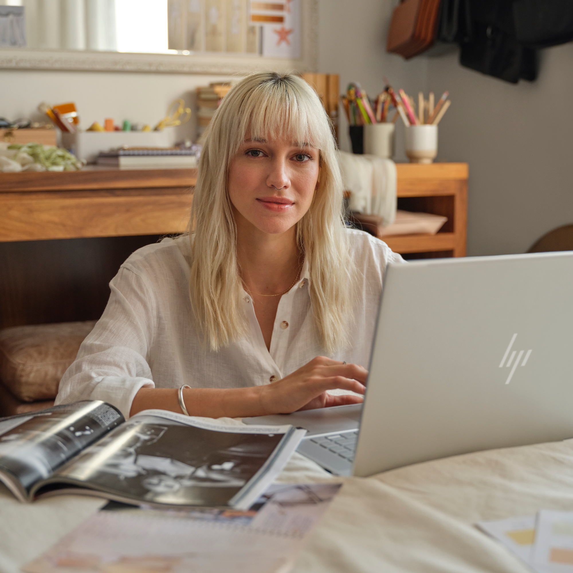 Blondwłosa kobieta siedzi przy laptopie z pobliskim magazynem.
