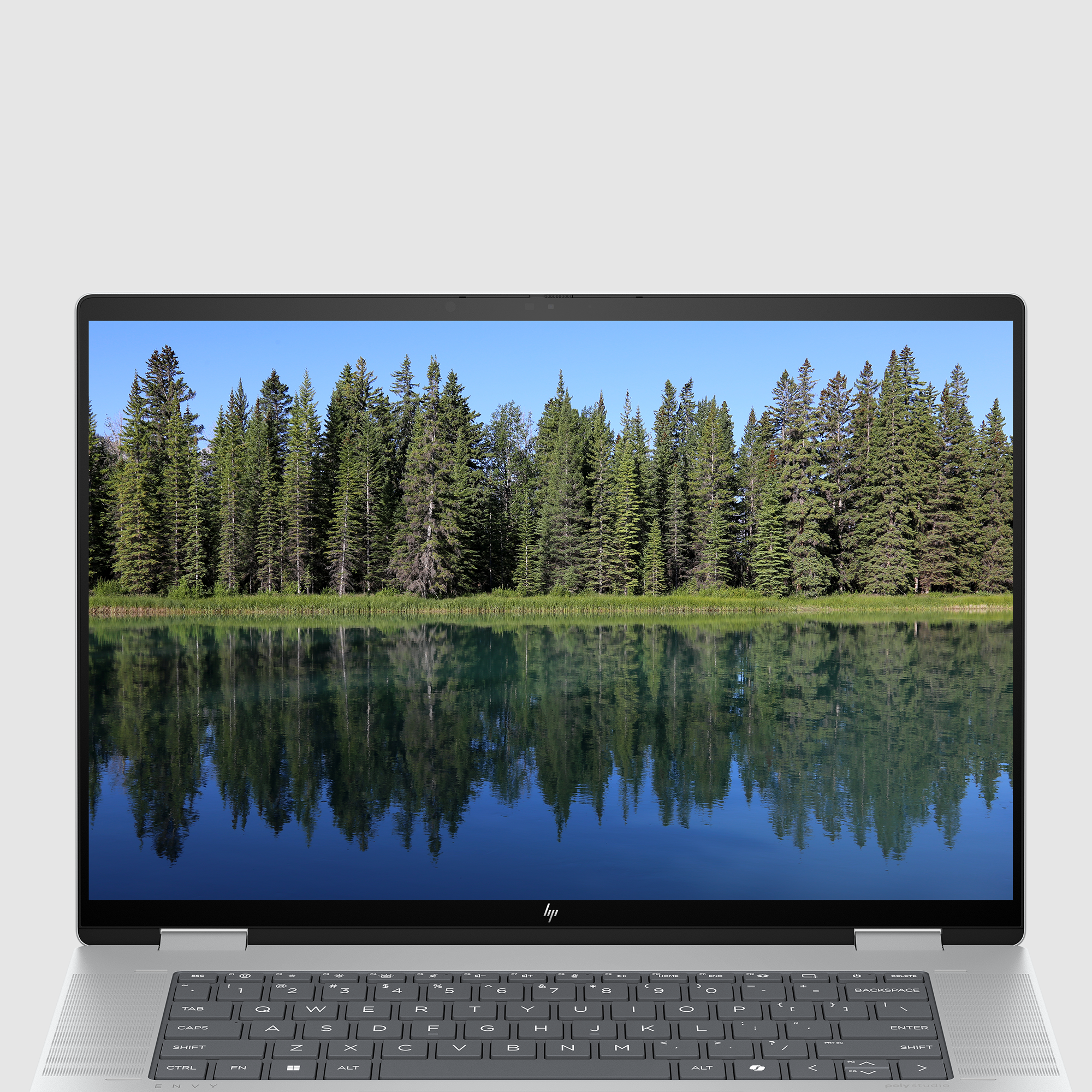 Laptop wyświetla odbicie drzew i nieba w spokojnym jeziorze.