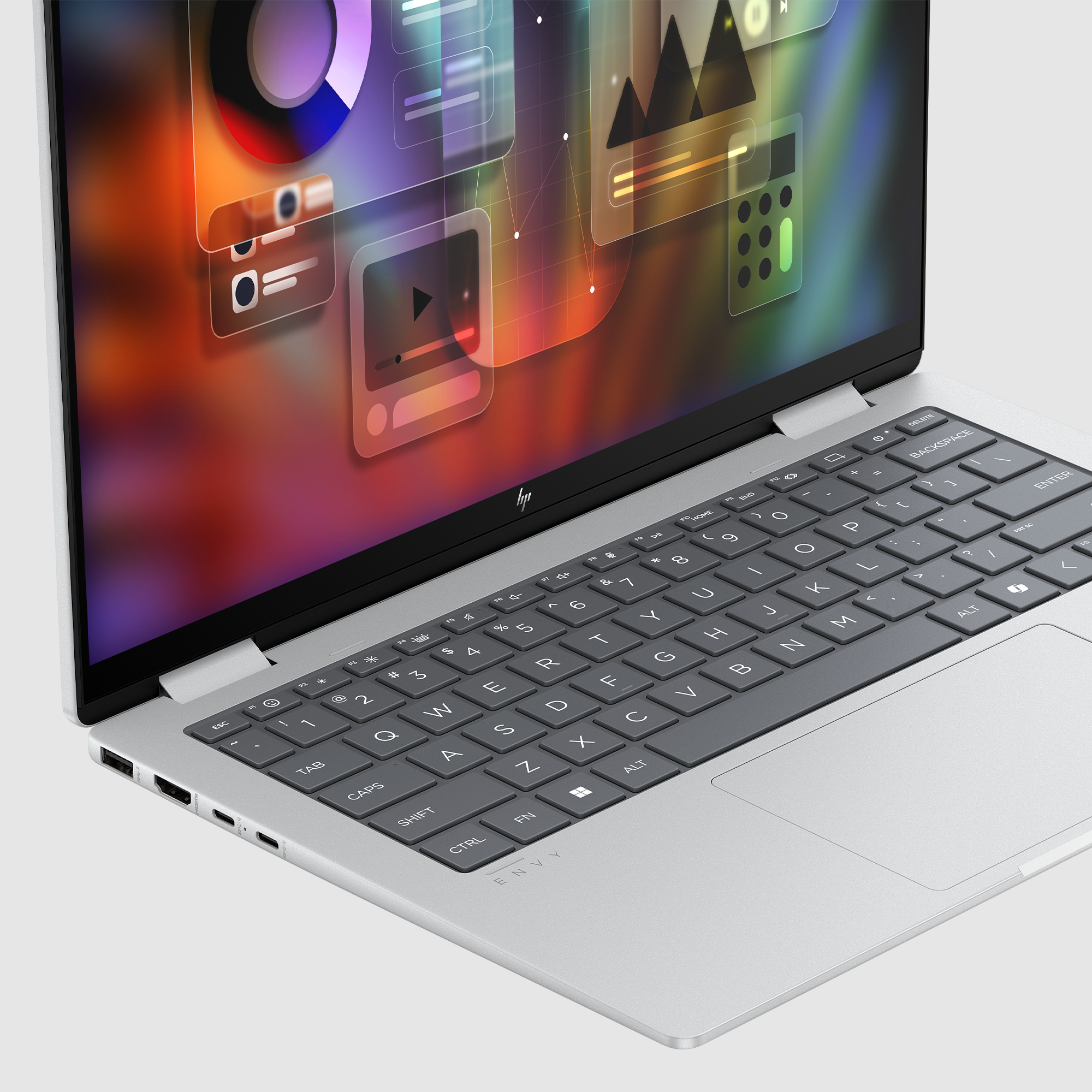 Srebrny laptop HP otwarty, pokazujący kolorowy abstrakcyjny interfejs na ekranie. Klawiatura widoczna.