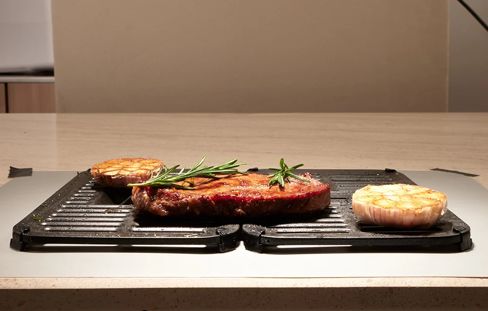 Egy steak rozmaringgal és sült fokhagymával egy grillen.
