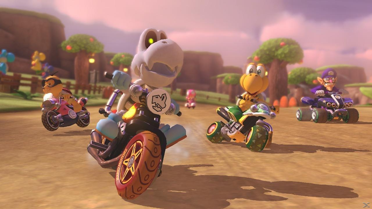 Dry Bones jedzie motocyklem w Mario Kart. Obecni są też Koopa Troopa i Waluigi.