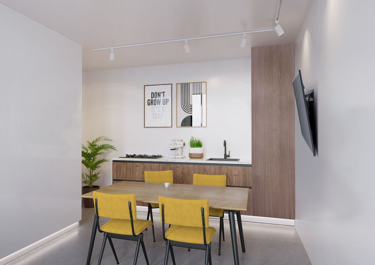 Jadalnia z żółtymi krzesłami przy drewnianym stole, kuchnia w tle.