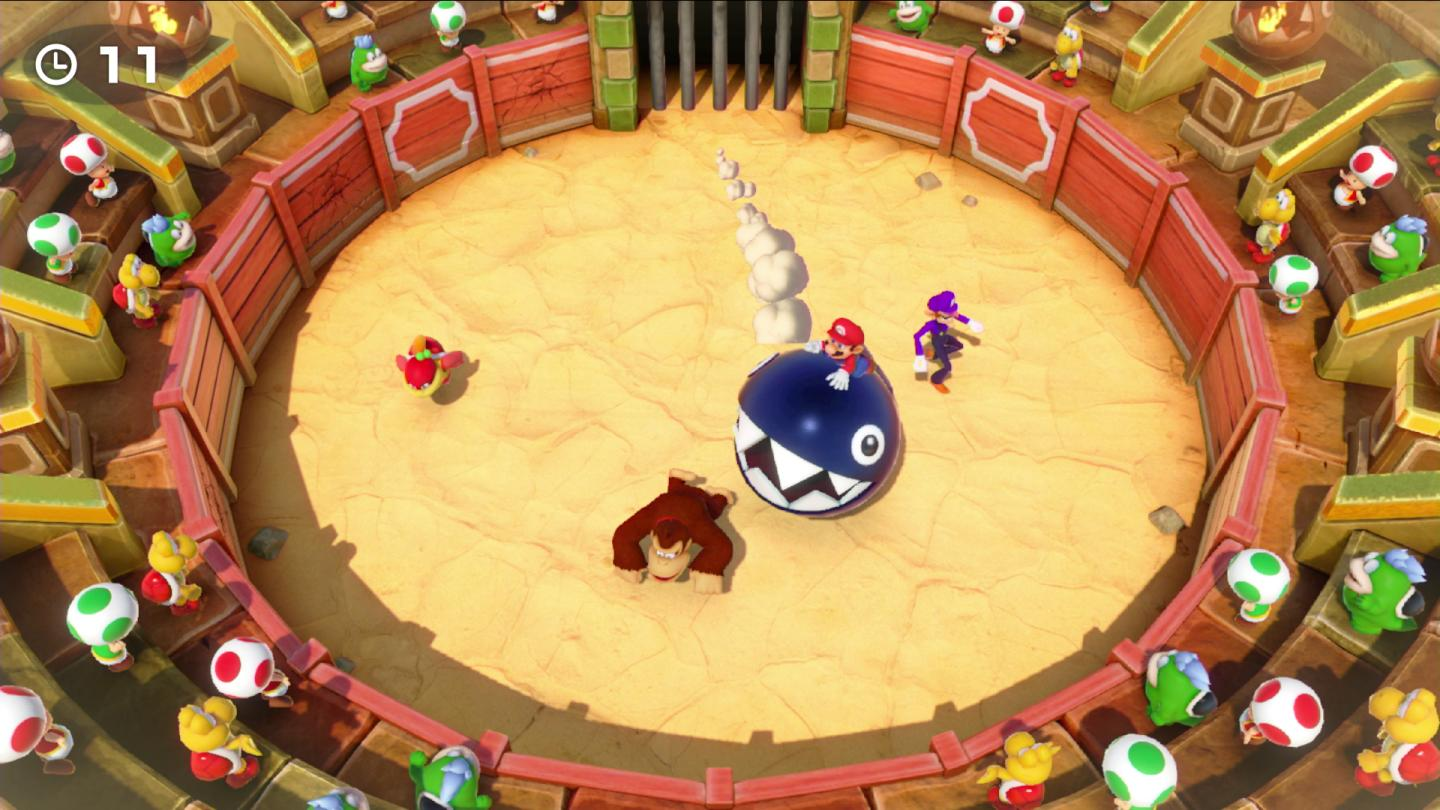 Mario jedzie na niebieskim Chain Chomp. Donkey Kong leży na ziemi. Waluigi stoi obok.
