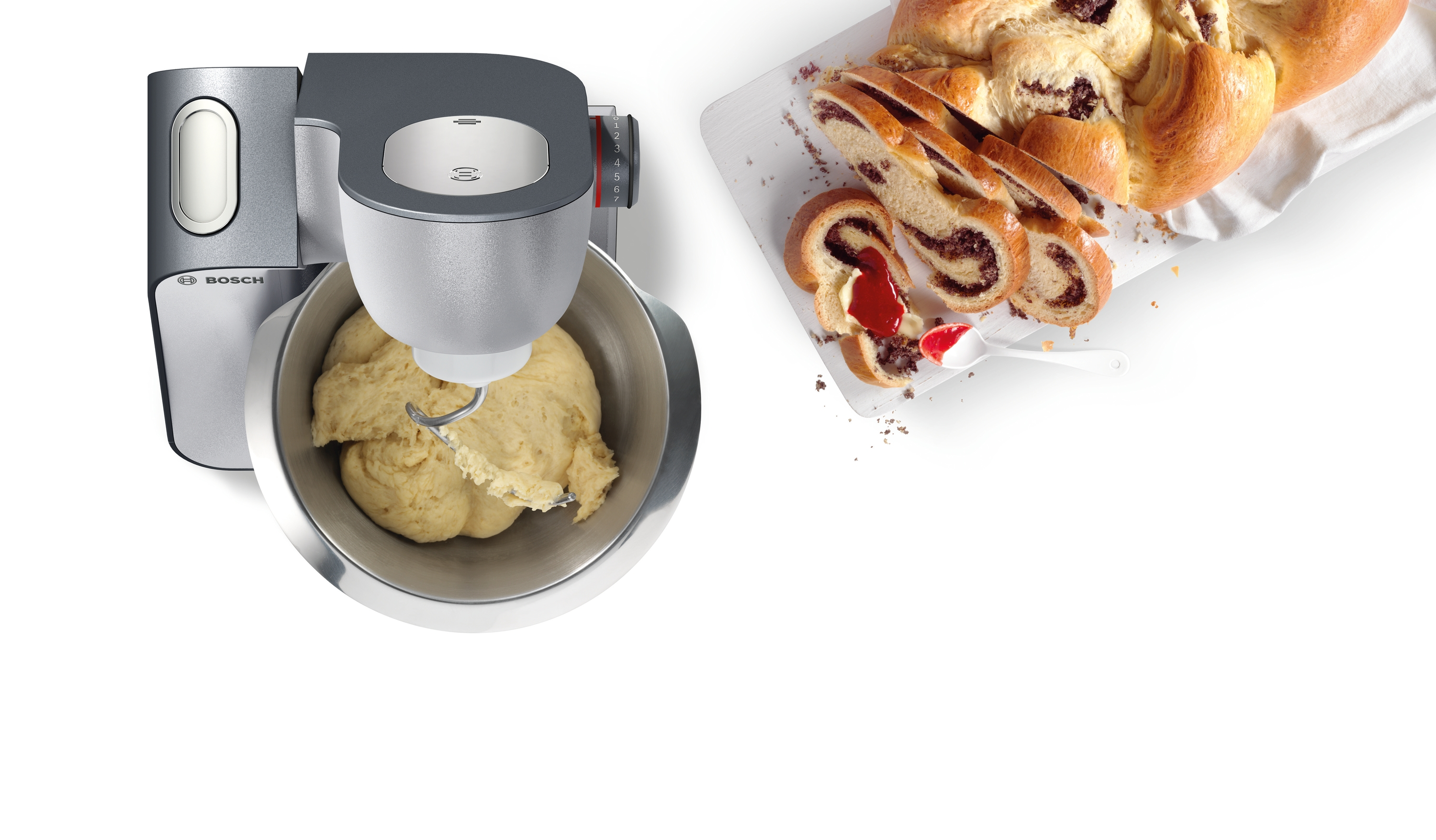 Robot kuchenny z ciastem i pokrojonym plackiem z orzechami na białej powierzchni.