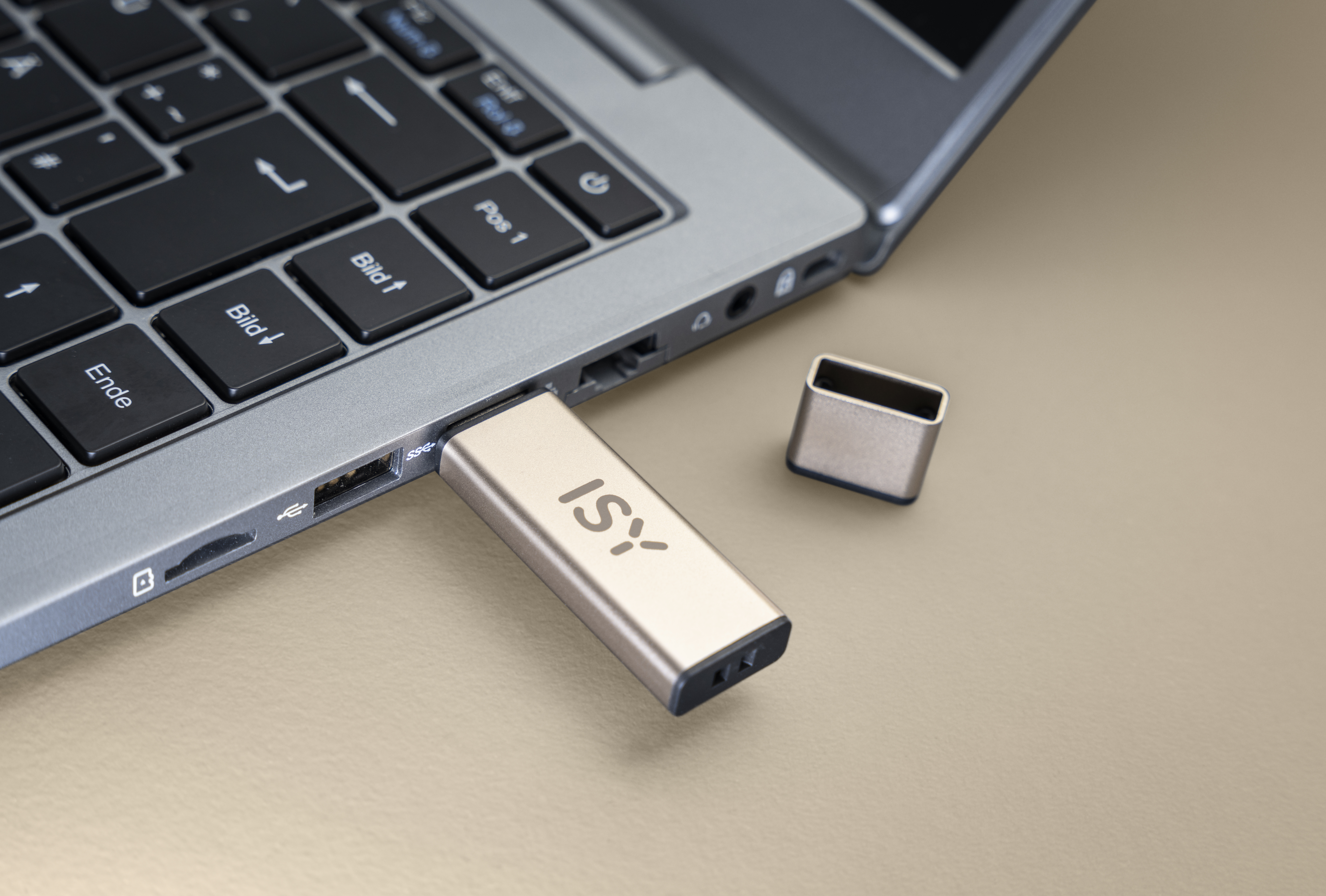Złoty pendrive podłączony do laptopa, z nakładką obok.