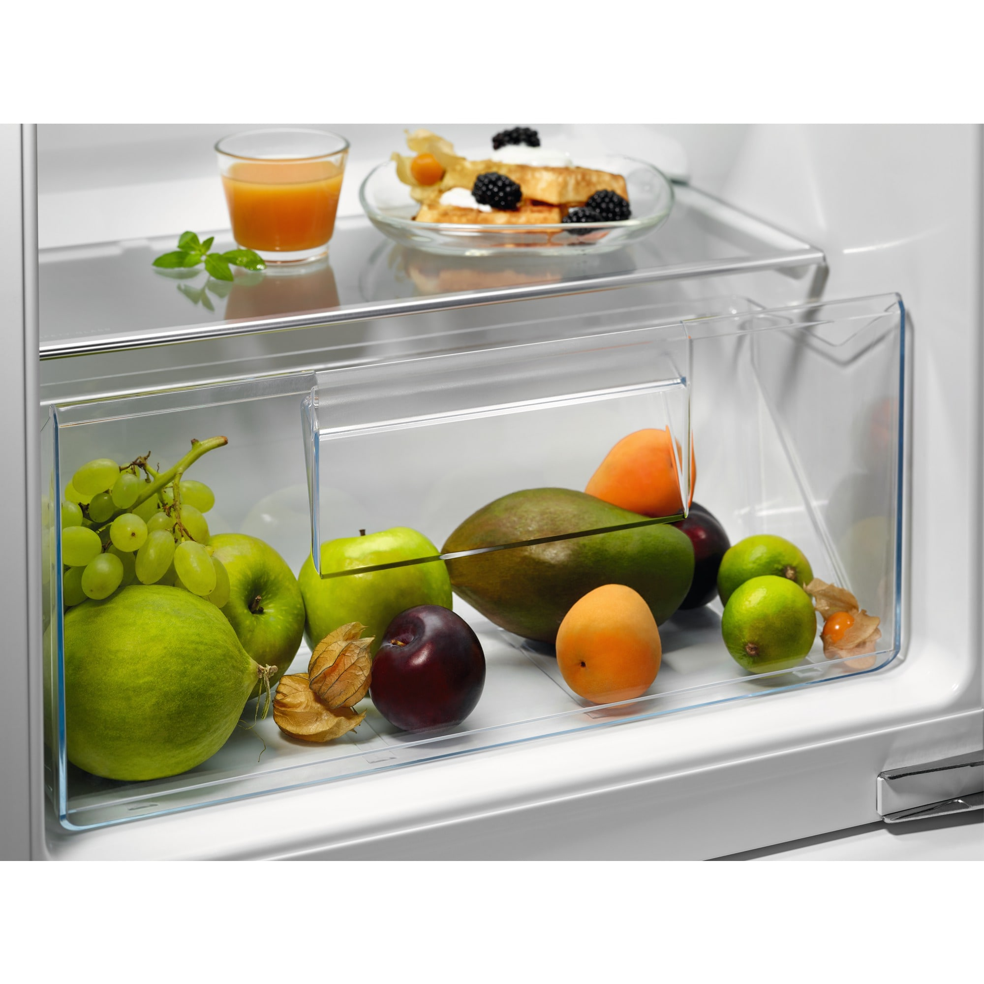 Owoce i sok w lodówce: winogrona, jabłka, mango, śliwki, morele, limonki, miechunka.