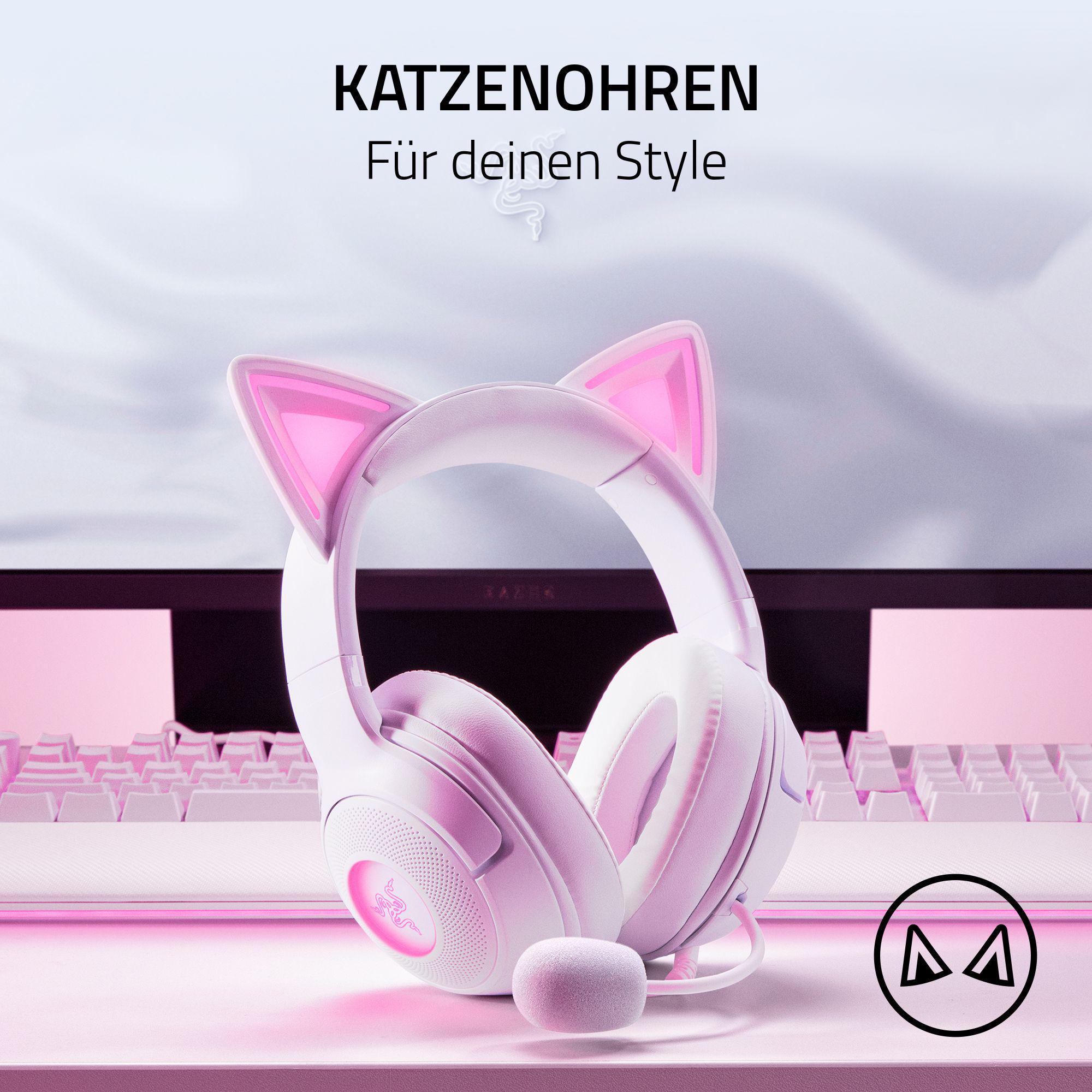 Weiße Kopfhörer mit rosa Katzenohren auf einem Schreibtisch mit Tastatur.