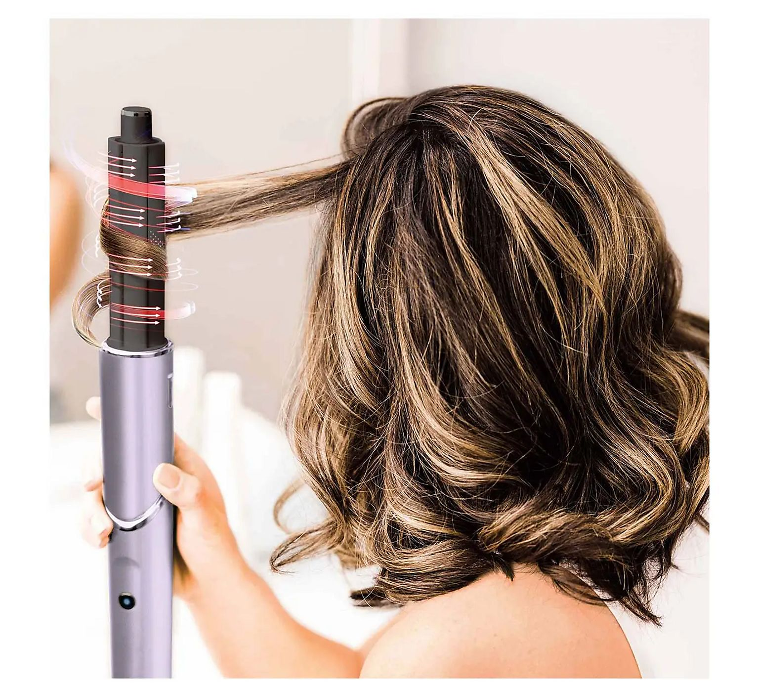 Une femme coiffe ses cheveux bruns avec un fer à friser automatique montrant des graphiques de flux d'air.