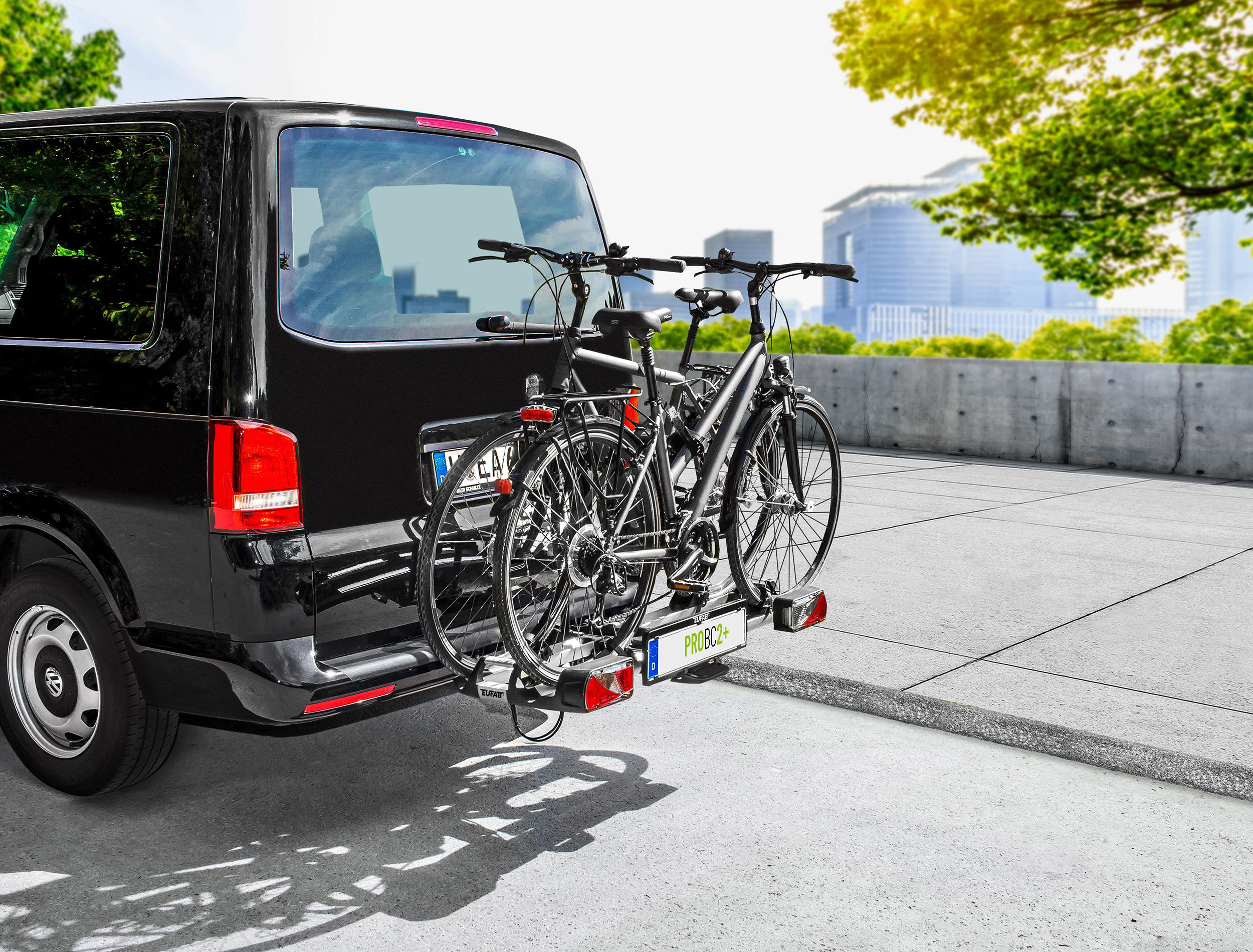 Schwarzer Transporter mit zwei Fahrrädern auf einem Heckträger.