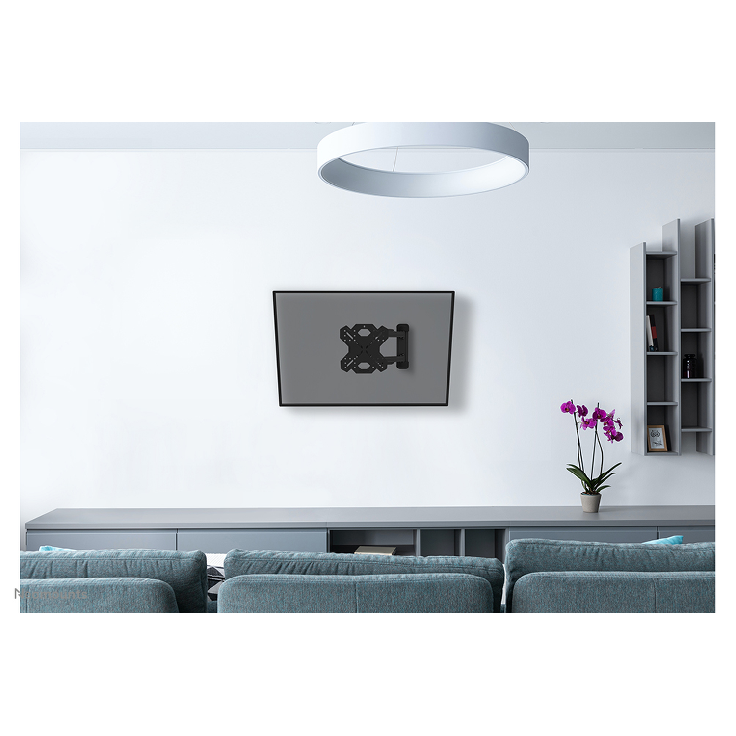 Een grijze tv-beugel aan een witte muur boven een bank.