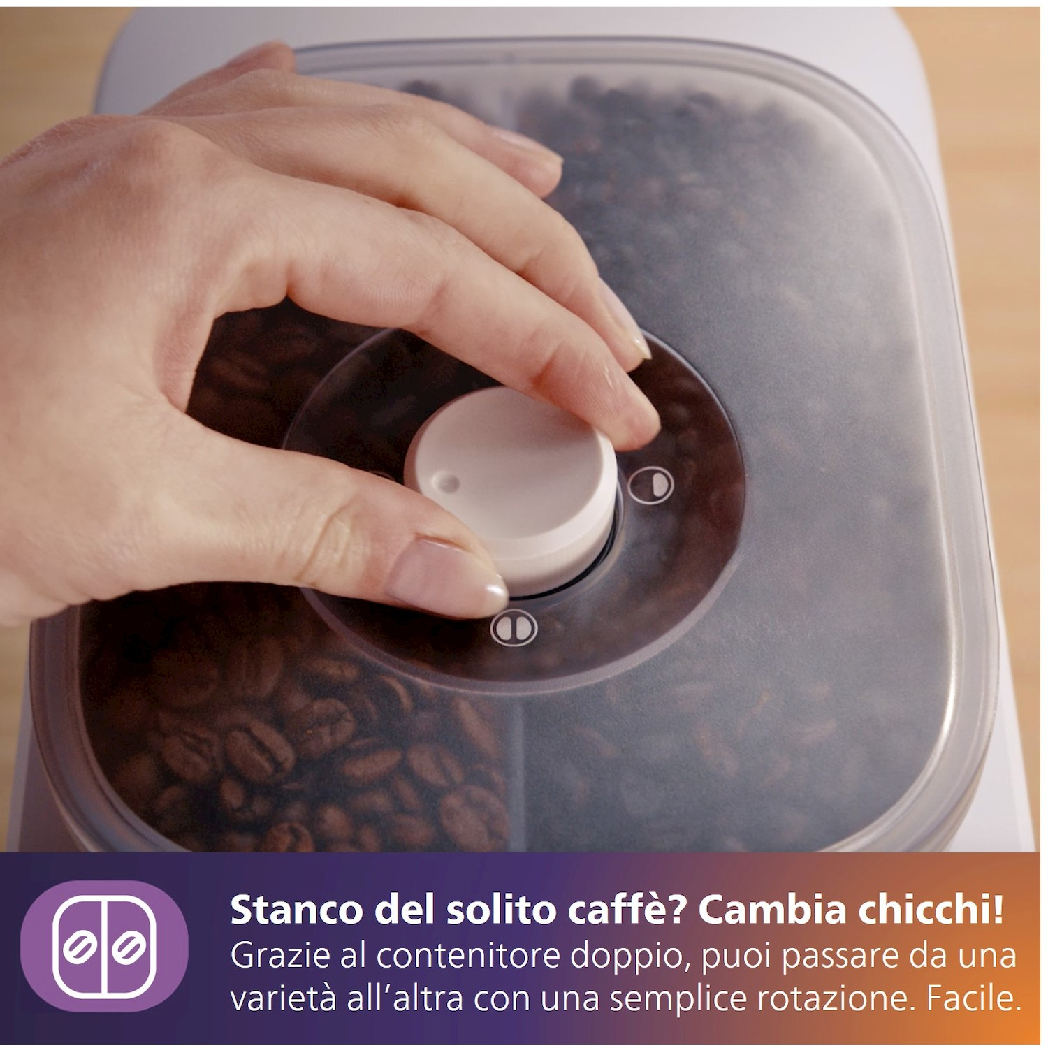 Una mano gira una manopola su un contenitore di chicchi di caffè.