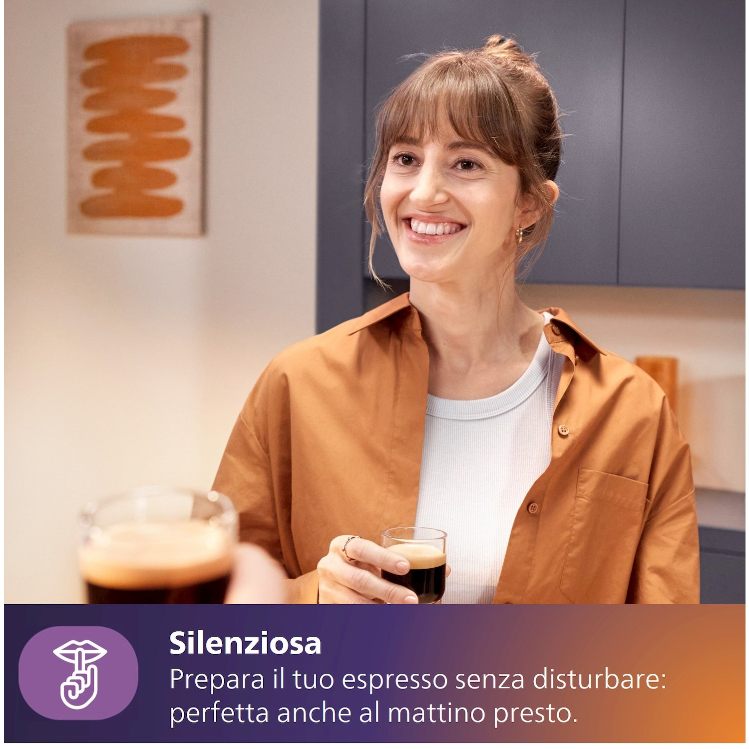 Una donna sorride, tiene un espresso. Una macchina da caffè è accennata.