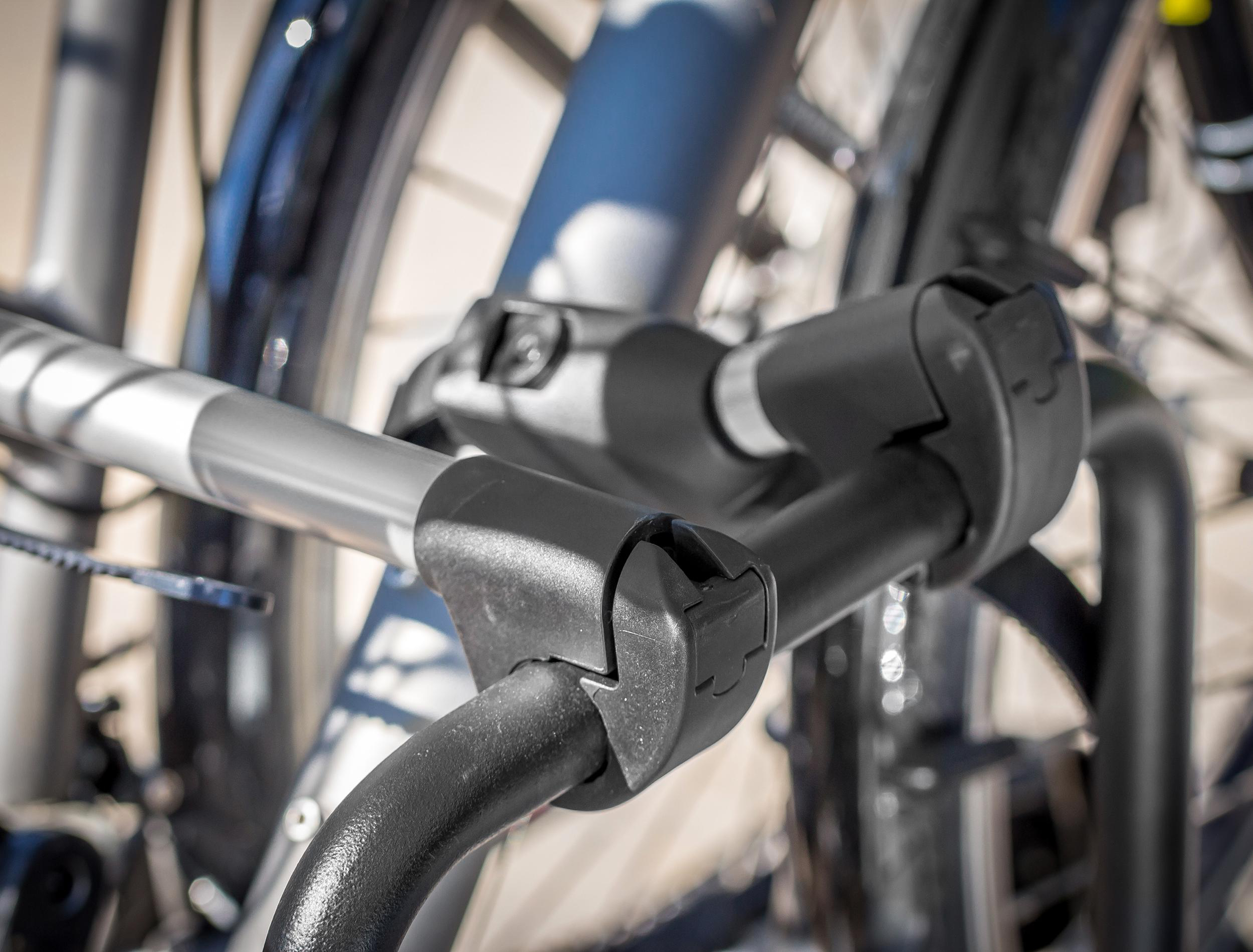 Fokus auf schwarzen Fahrradträgerteilen mit silbernem Griff. Räder im Hintergrund.