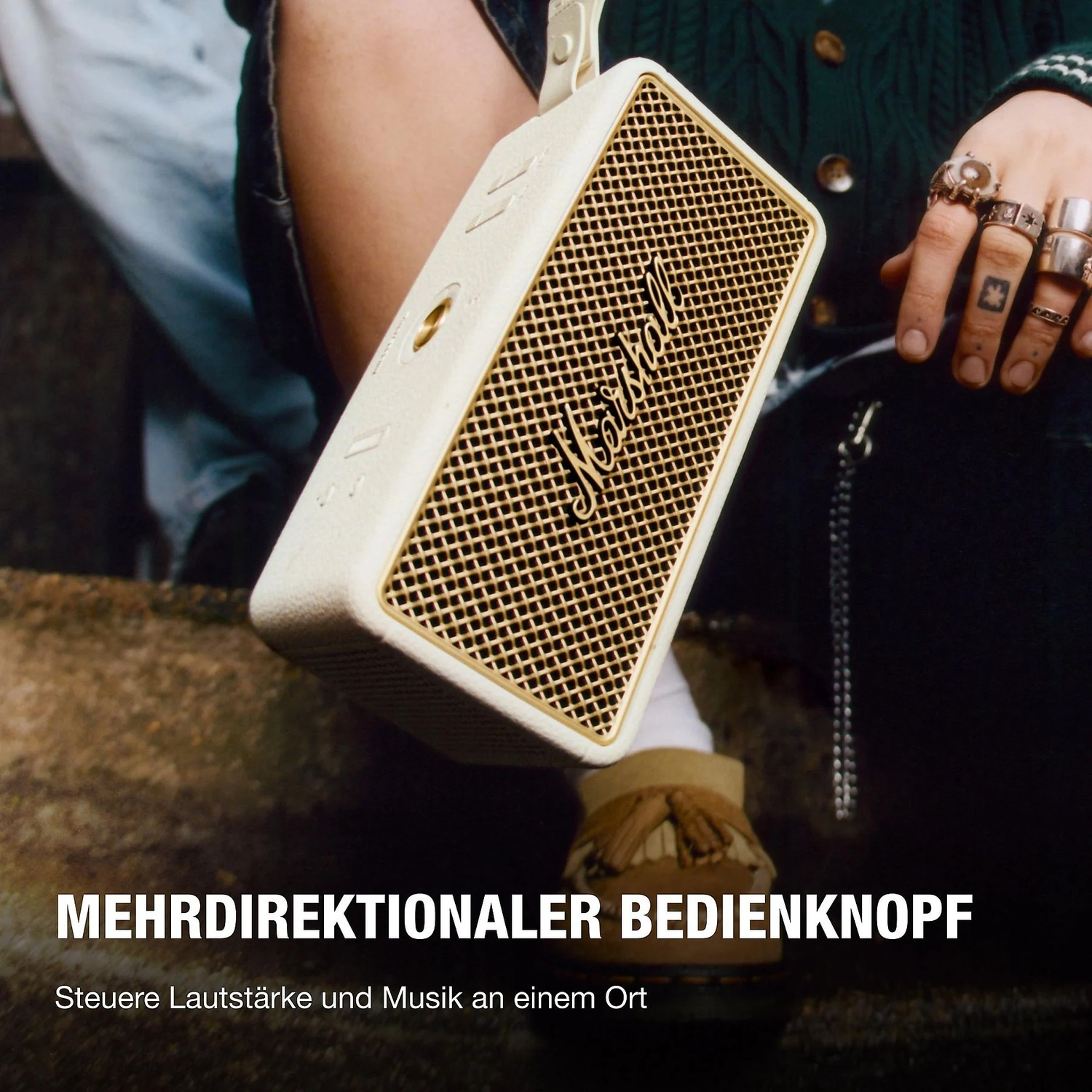 Een beige Marshall luidspreker wordt vastgehouden. Gouden grille voorkant.