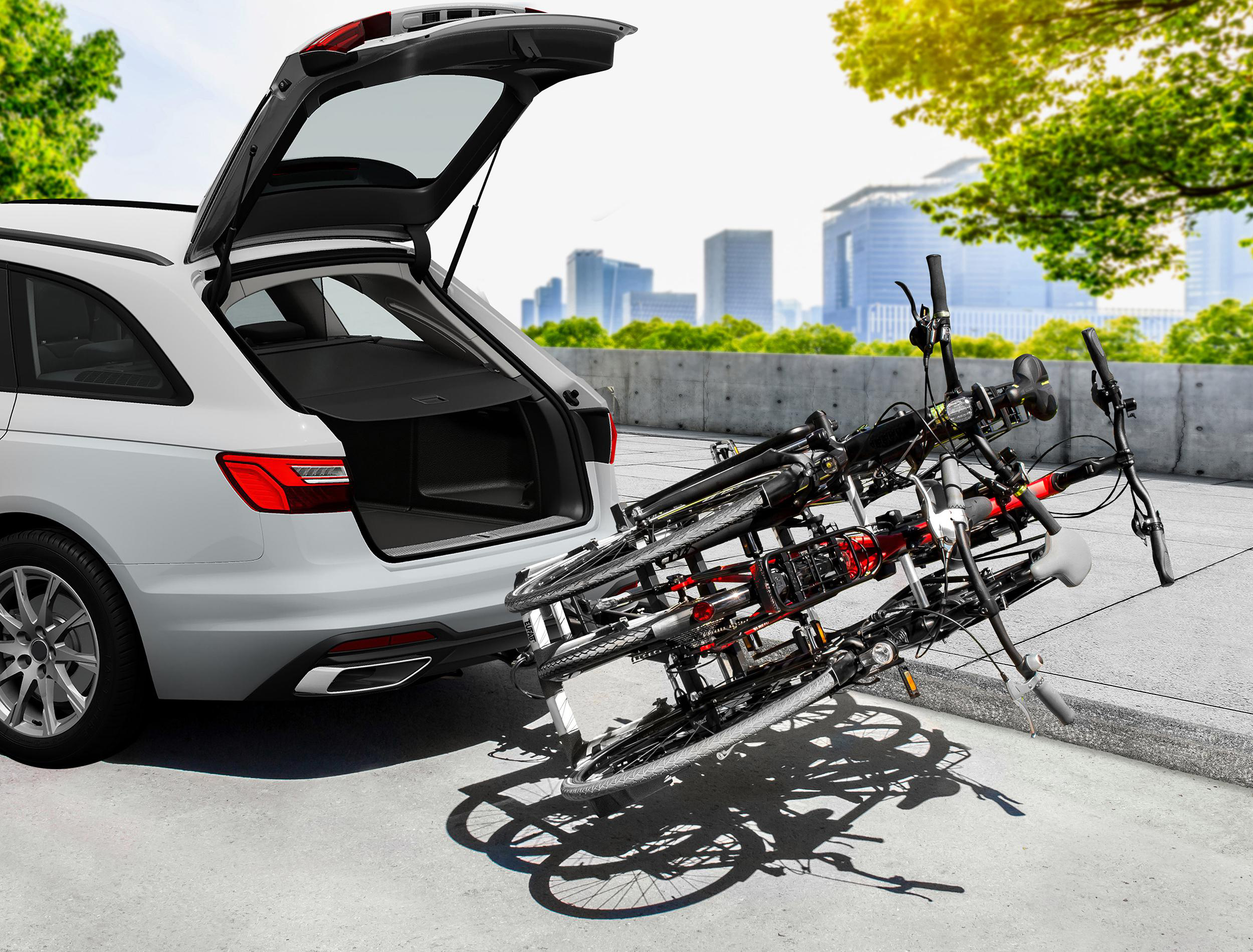 Ein weißer Kombi mit geöffneter Heckklappe und montiertem Fahrradträger mit Fahrrädern.