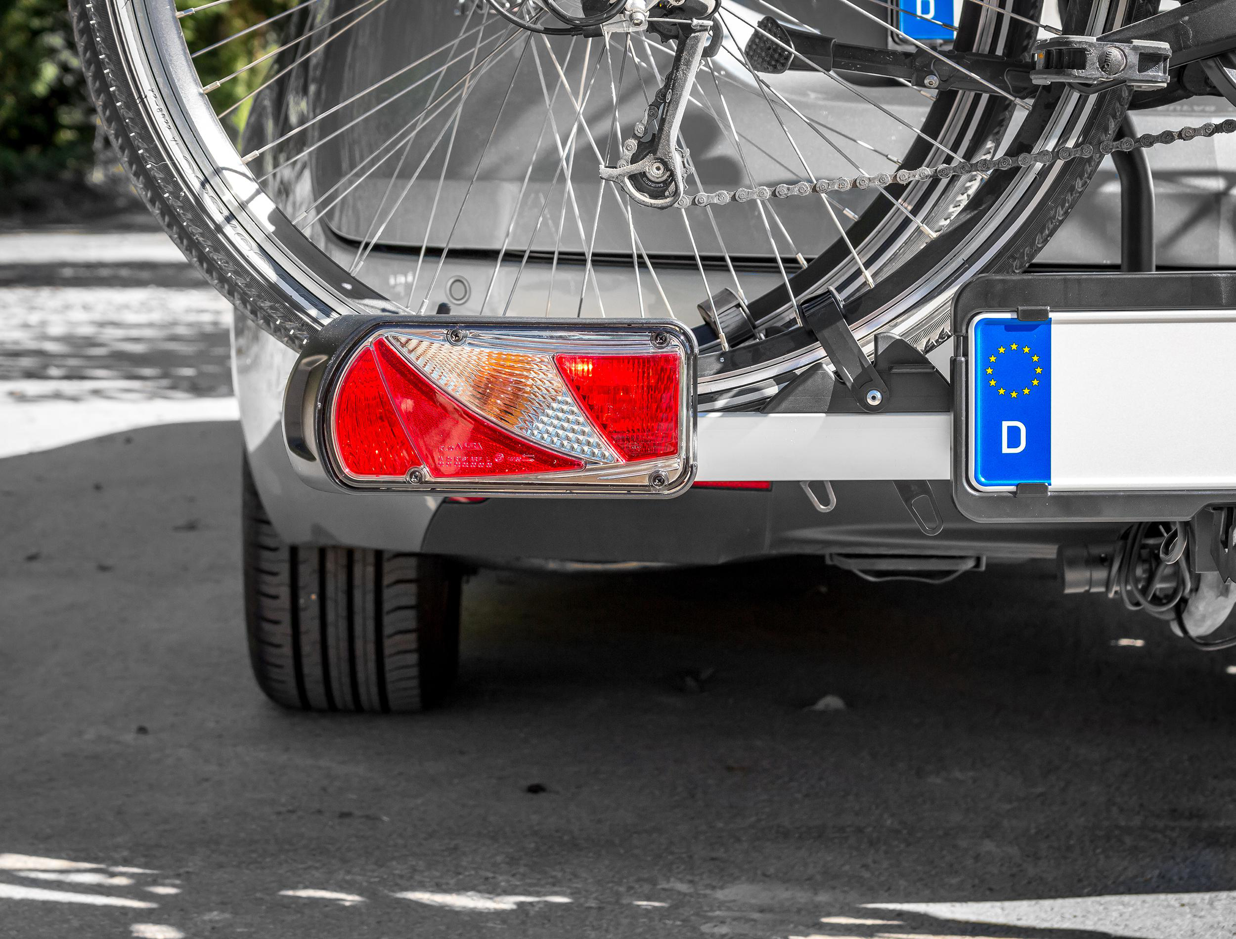 Ein Fahrradträger mit Fahrrad ist am Heck eines Autos befestigt. Deutsche Kennzeichen sind sichtbar.